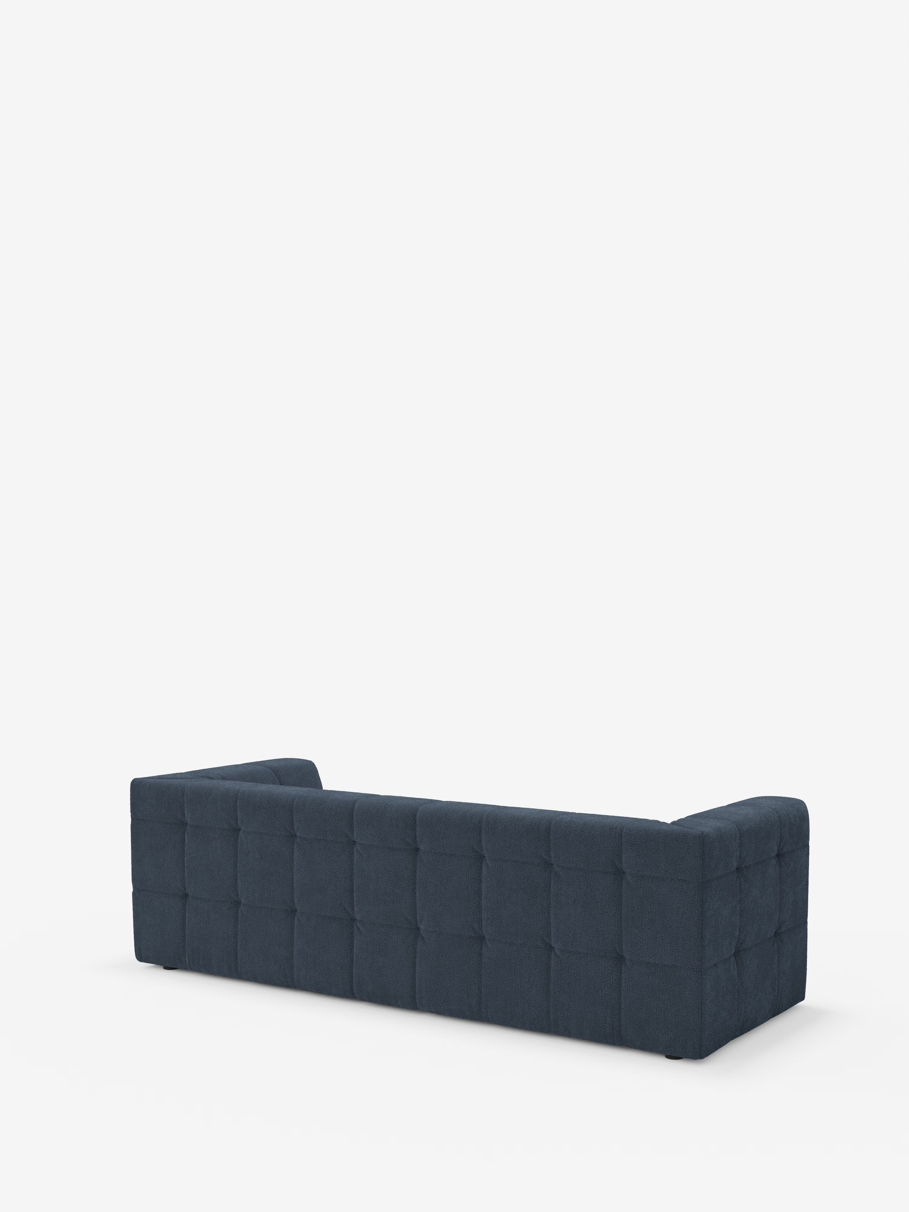 Il divano modulare Mosaic Divano a 3 e 4 posti, di colore blu scuro, di forma rettangolare e con schienale basso, realizzato in bouclé da Divani.Store, presenta un motivo a griglia capitonné sullo schienale e sui fianchi. L'immagine, che mostra il divano visto da dietro su uno sfondo bianco a tinta unita, mette in risalto il rivestimento in tessuto T21 antimacchia ed esalta le linee moderne e pulite del divano.