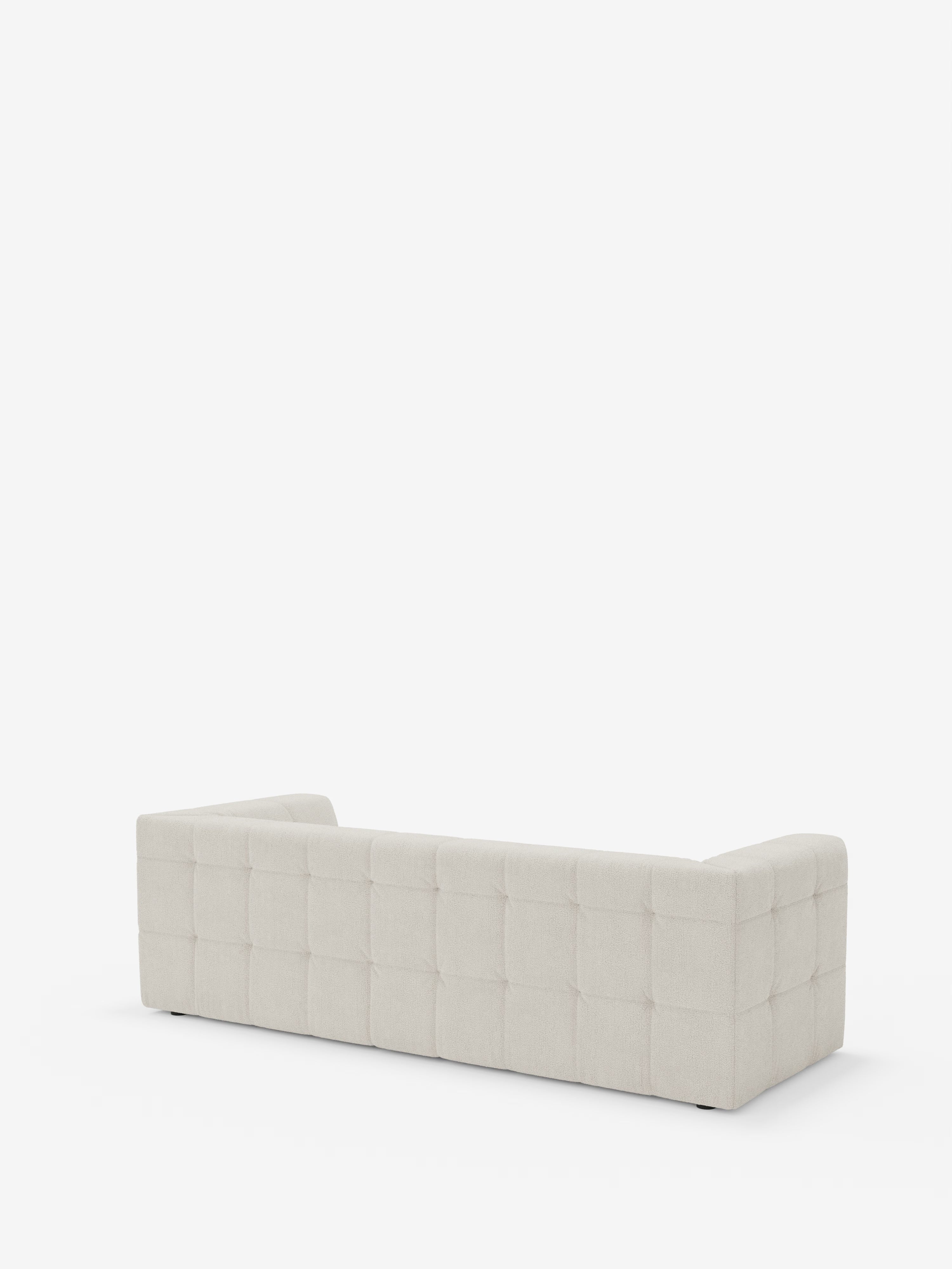 Un divano modulare Mosaic a 3 e 4 posti di Divani.Store, qui presentato in bouclé beige chiaro con schienale basso, braccioli squadrati e caratteristici dettagli capitonné (a griglia trapuntata) sullo schienale e sui fianchi. Ripreso di retro su uno sfondo bianco, mette in risalto il rivestimento in tessuto T21 smacchiabile dalla trama rigata e la silhouette squadrata e contemporanea.