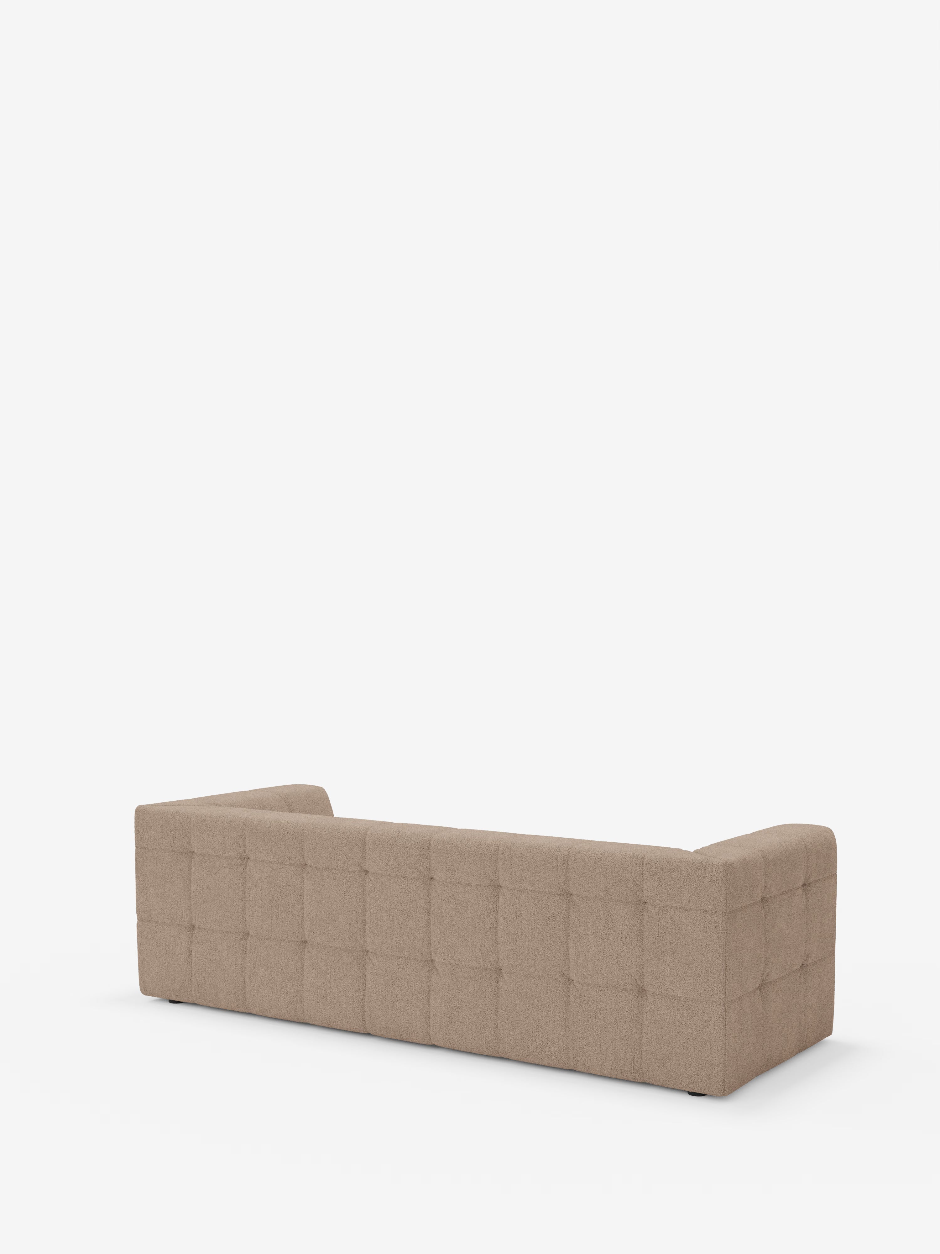 Un divano modulare Mosaic Divano a 3 e 4 posti color beige in bouclé di Divani.Store, caratterizzato da schienale e braccioli trapuntati con motivo a quadrati, braccioli dal profilo ribassato e rivestimento in tessuto T21 antimacchia. Il design minimalista di questo divano moderno è caratterizzato da linee rette e dall’assenza di gambe a vista, come si può notare dalla vista posteriore su uno sfondo bianco a tinta unita.