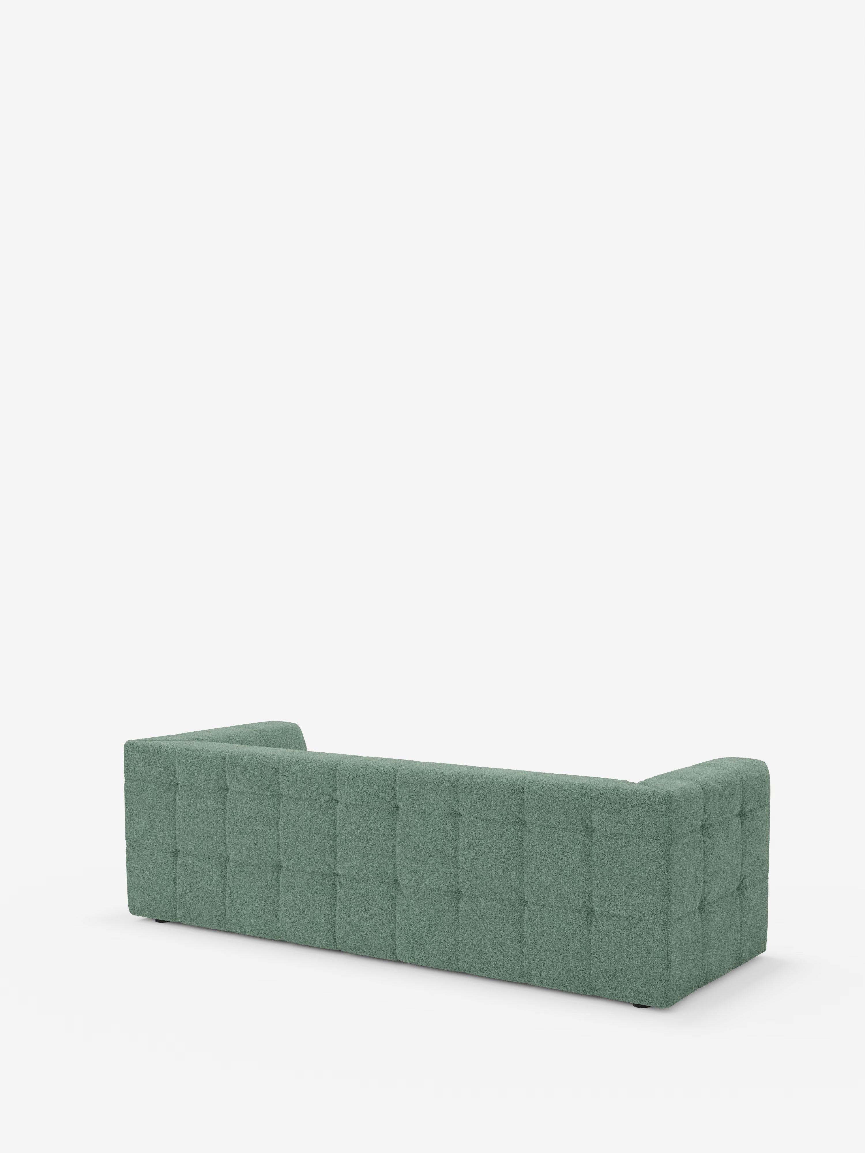 Un divano modulare Mosaic a 3 e 4 posti, verde, moderno e di forma rettangolare, realizzato in bouclé: capitonné e design in tessuto antimacchia T21 di Divani.Store, è ripreso dall’angolo posteriore sinistro. Il divano presenta una trapuntatura a motivi quadrati sullo schienale e sui fianchi. Lo sfondo bianco a tinta unita mette in risalto il colore vivace e il disegno geometrico di questo divano modulare.
