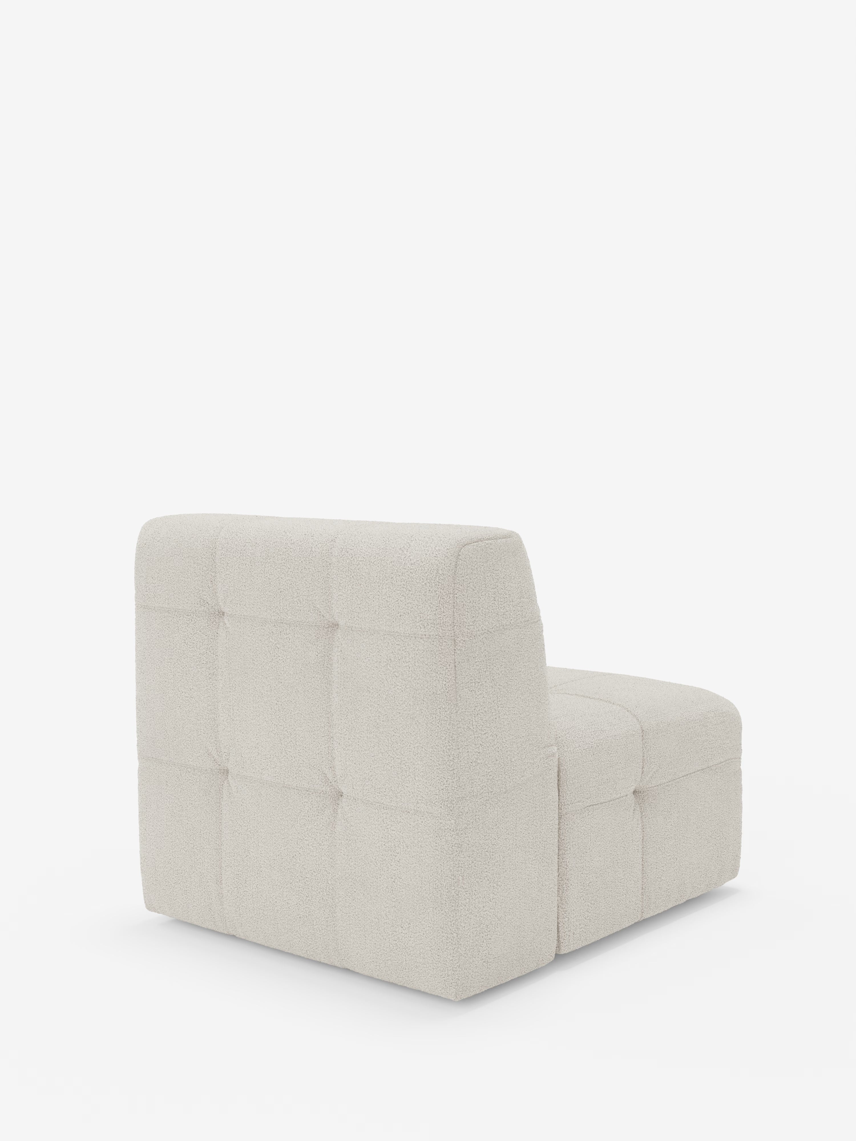 Vi presentiamo la poltrona Mosaic Modulo da 77 cm di Divani.Store: una poltrona contemporanea senza braccioli realizzata in Italia. Questo modello è caratterizzato da un ampio schienale squadrato e da una seduta bassa e profonda, il tutto rivestito in tessuto bouclé T21 beige chiaro, di facile manutenzione, con un caratteristico motivo a griglia capitonné. Nella foto è raffigurata vista da dietro su uno sfondo bianco a tinta unita.