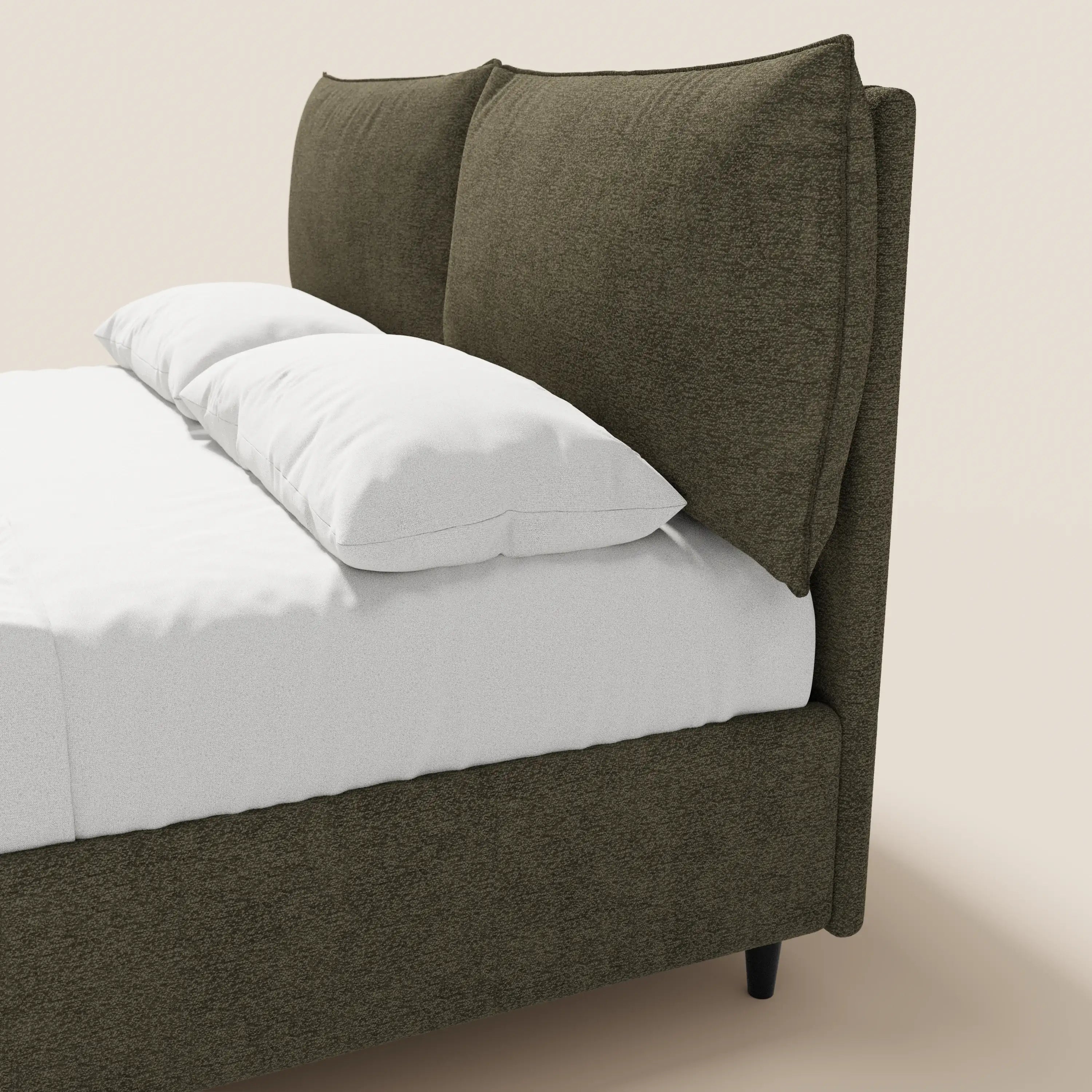 Il letto imbottito ZAYRON di Letti.store presenta una moderna struttura in tessuto verde oliva certificata Oeko-Tex®, due grandi cuscini regolabili, lenzuola bianche e gambe corte nere, il tutto raffigurato su uno sfondo beige a tinta unita.