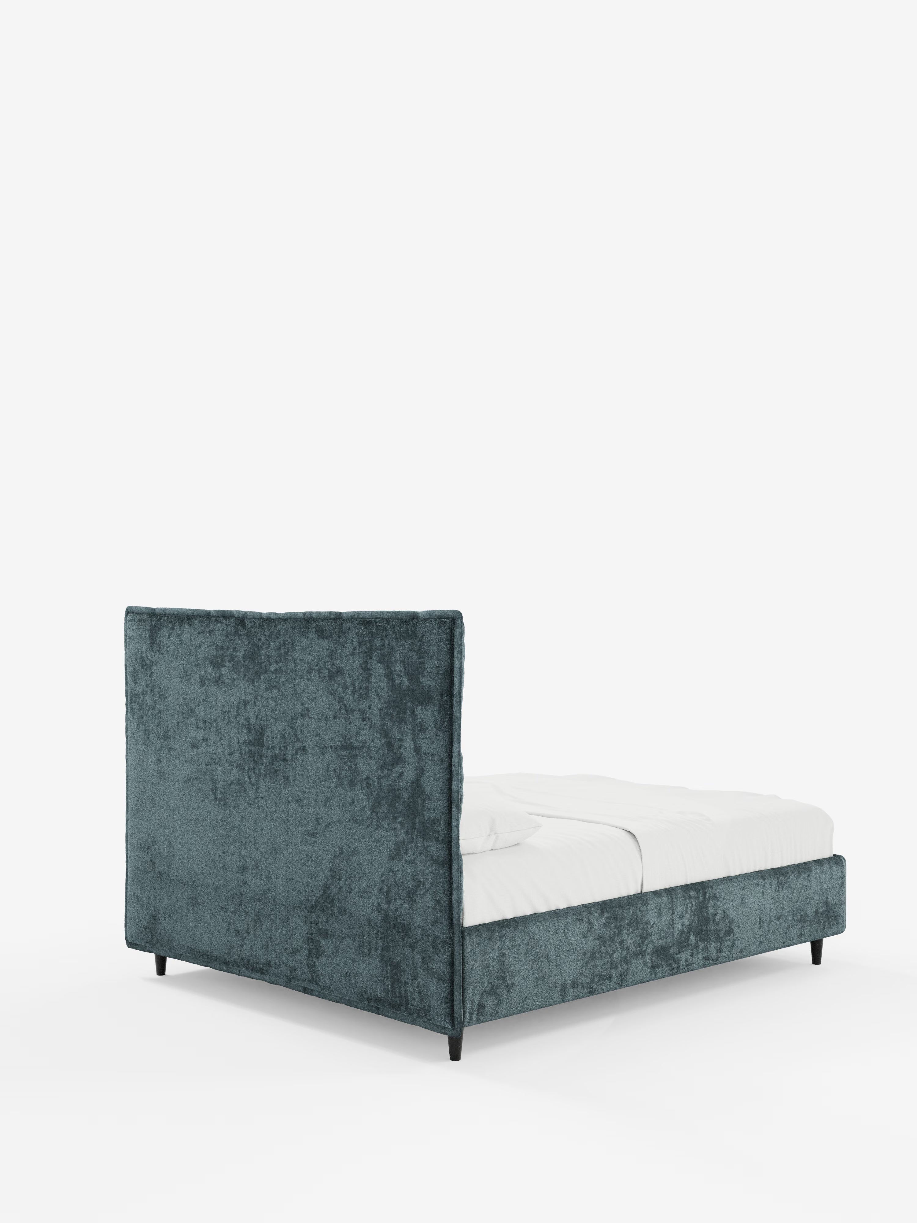 Il letto imbottito AURO con contenitore e testiera alta capitonné in ciniglia Oeko-Tex® di Letti.store presenta una struttura rivestita in velluto color verde acqua con una testiera alta e rettangolare capitonné, una pediera bassa e gambe corte nere. Questo elegante letto imbottito con contenitore è abbinato a un lenzuolo con angoli bianco e a una coperta, e fa da contrasto con uno sfondo bianco a tinta unita.