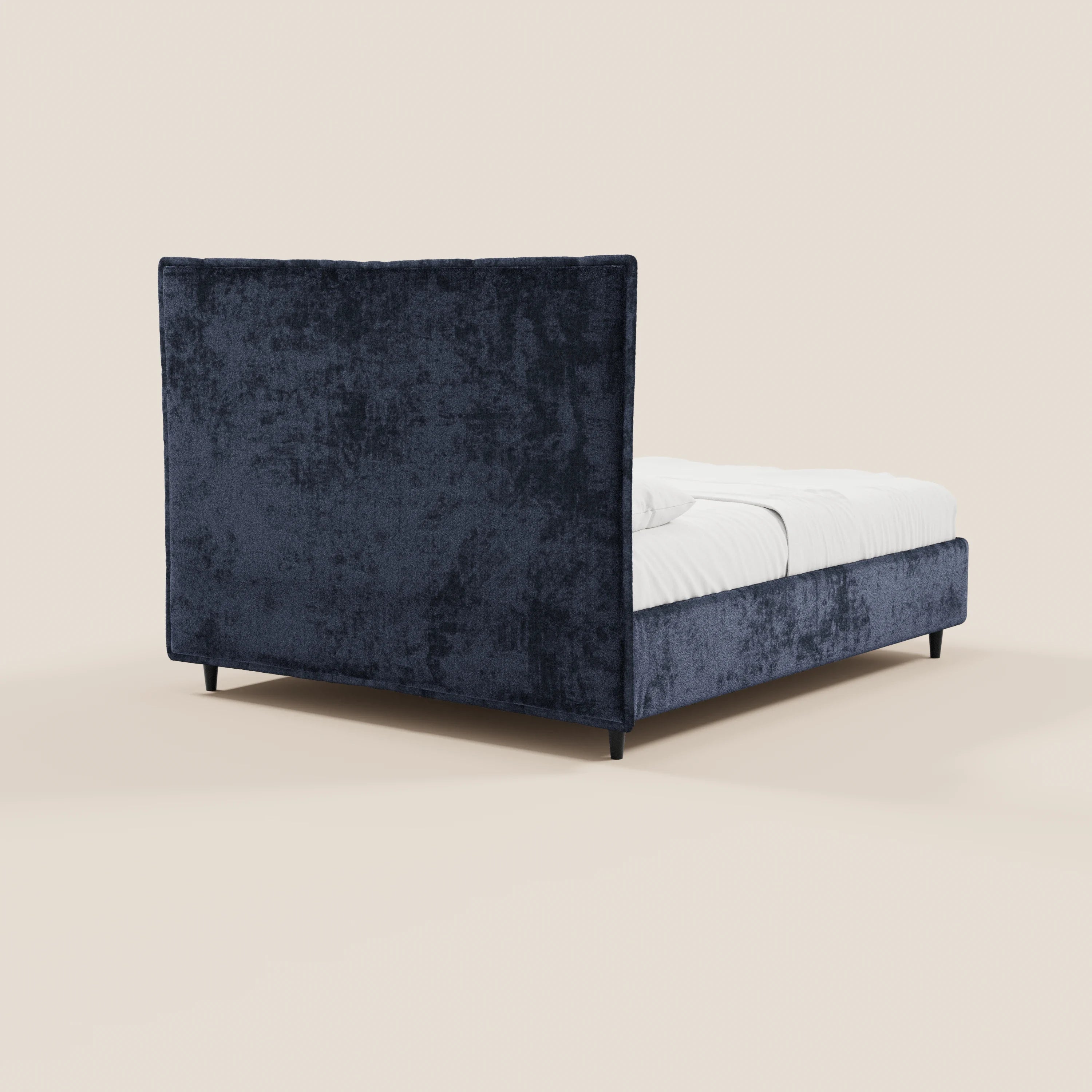 Il letto imbottito AURO di Letti.store presenta una testiera alta capitonné in ciniglia certificata Oeko-Tex®, una base contenitiva e poggia su gambe corte nere con biancheria da letto bianca, il tutto su uno sfondo beige a tinta unita.