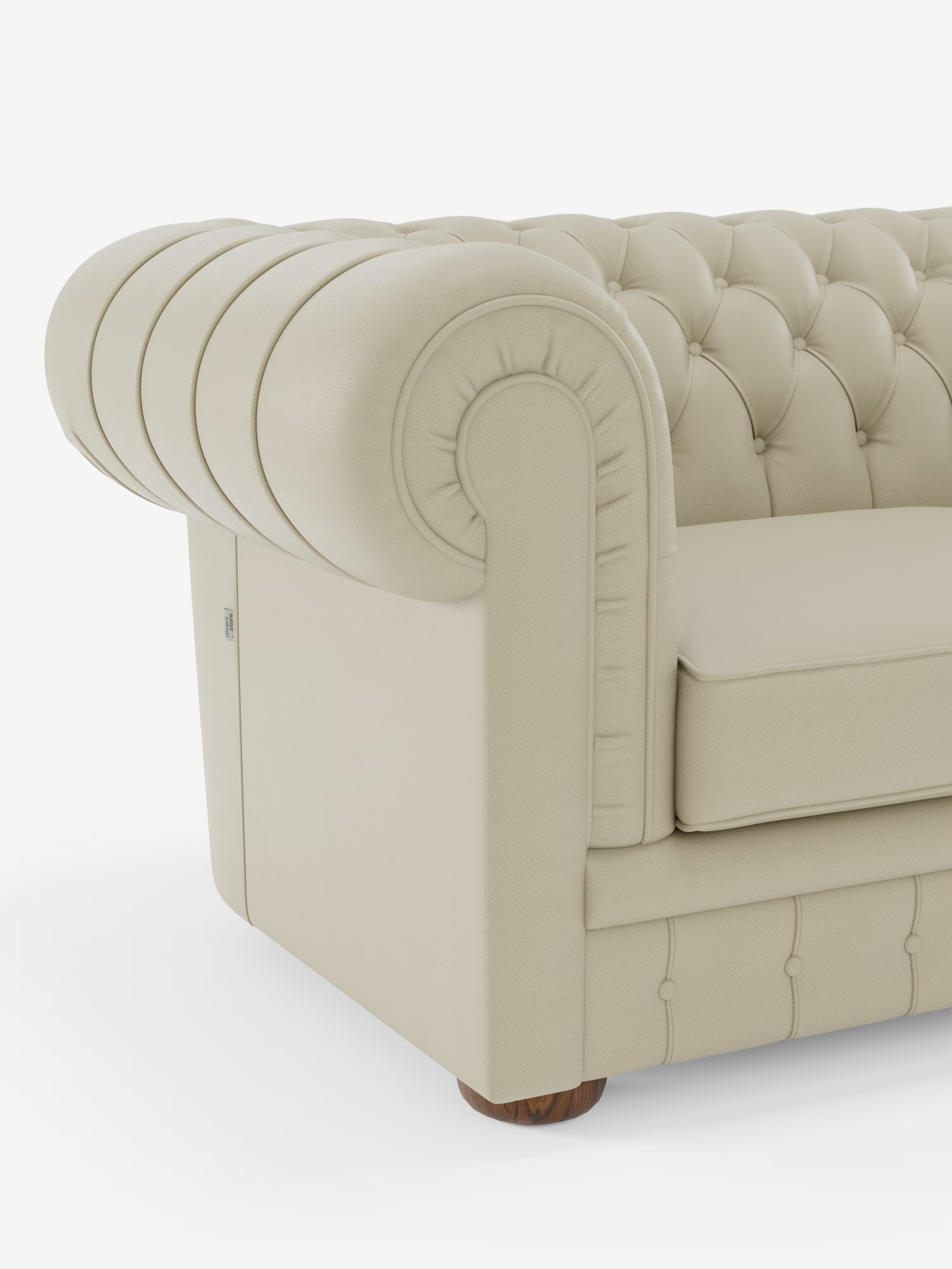Primo piano del Chester – Divano Chesterfield in vera pelle spessorata a 2 e 3 posti di Divani.Store, con finitura beige. L'immagine mette in risalto i braccioli arrotondati, la trapuntatura a bottoni e l'imbottitura morbida di questo divano artigianale Made in Italy. Il divano poggia su gambe corte e rotonde in legno, su uno sfondo bianco a tinta unita.