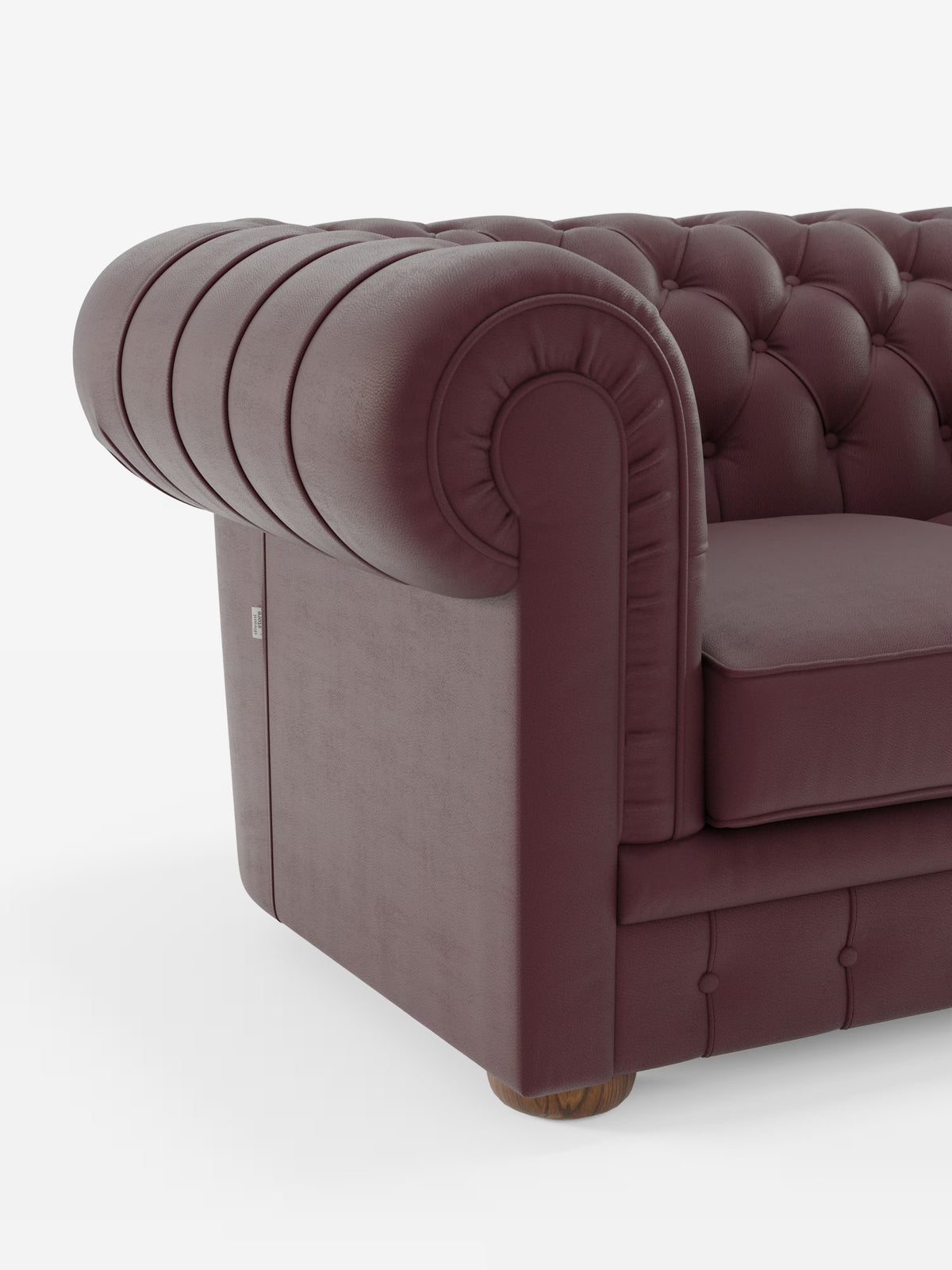 Primo piano del Divani.Store Chester 4 Posti 3 sedute in Vera Pelle – Chesterfield Capitonné Artigianale, che mette in risalto il rivestimento in vera pelle bordeaux con schienale capitonné, braccioli arrotondati caratterizzati da profonde pieghe e morbido cuscino di seduta. L’angolo del divano lascia intravedere il pavimento in legno sottostante, che fa da contrasto allo sfondo bianco.