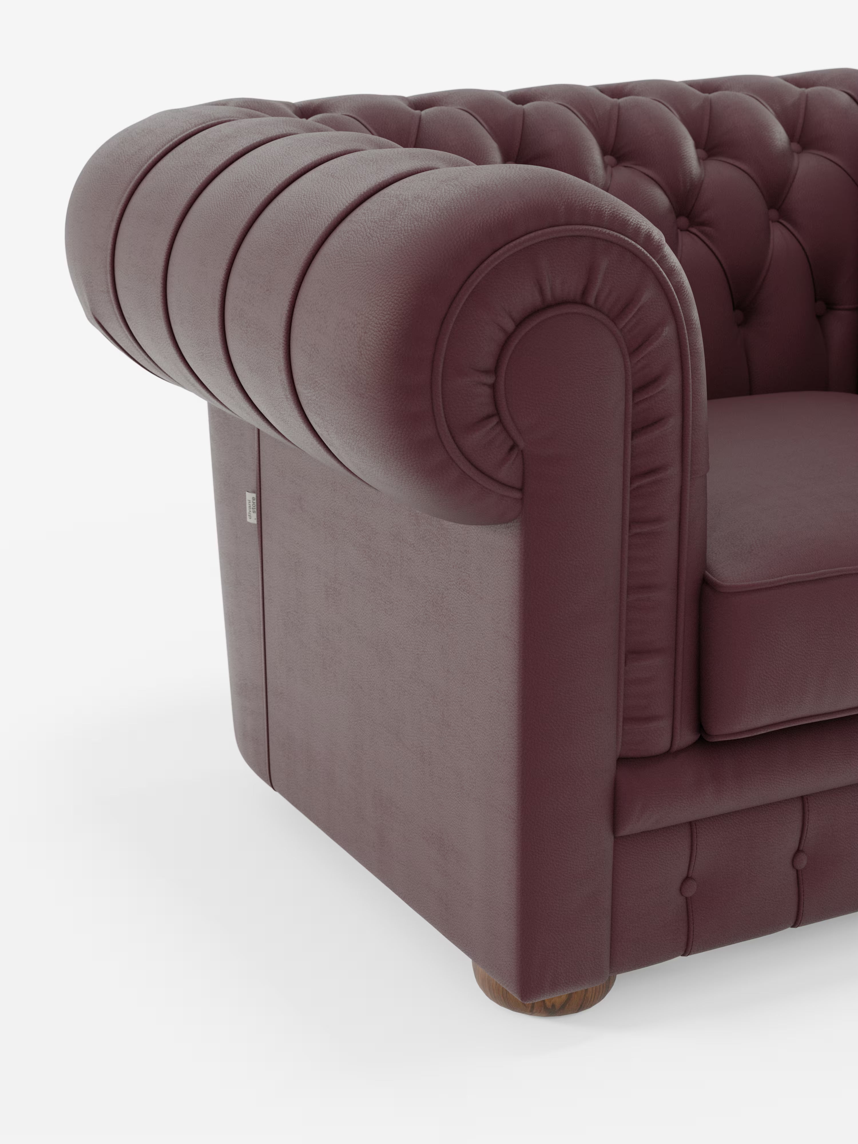 Primo piano del bracciolo della poltrona Chester di Divani.Store, realizzata in vera pelle spessorata con capitonné artigianale, caratterizzata da rivestimento in pelle color bordeaux, schienale profondamente trapuntato, bracciolo arrotondato con dettagli plissettati, seduta imbottita e gambe in legno su uno sfondo bianco liscio.