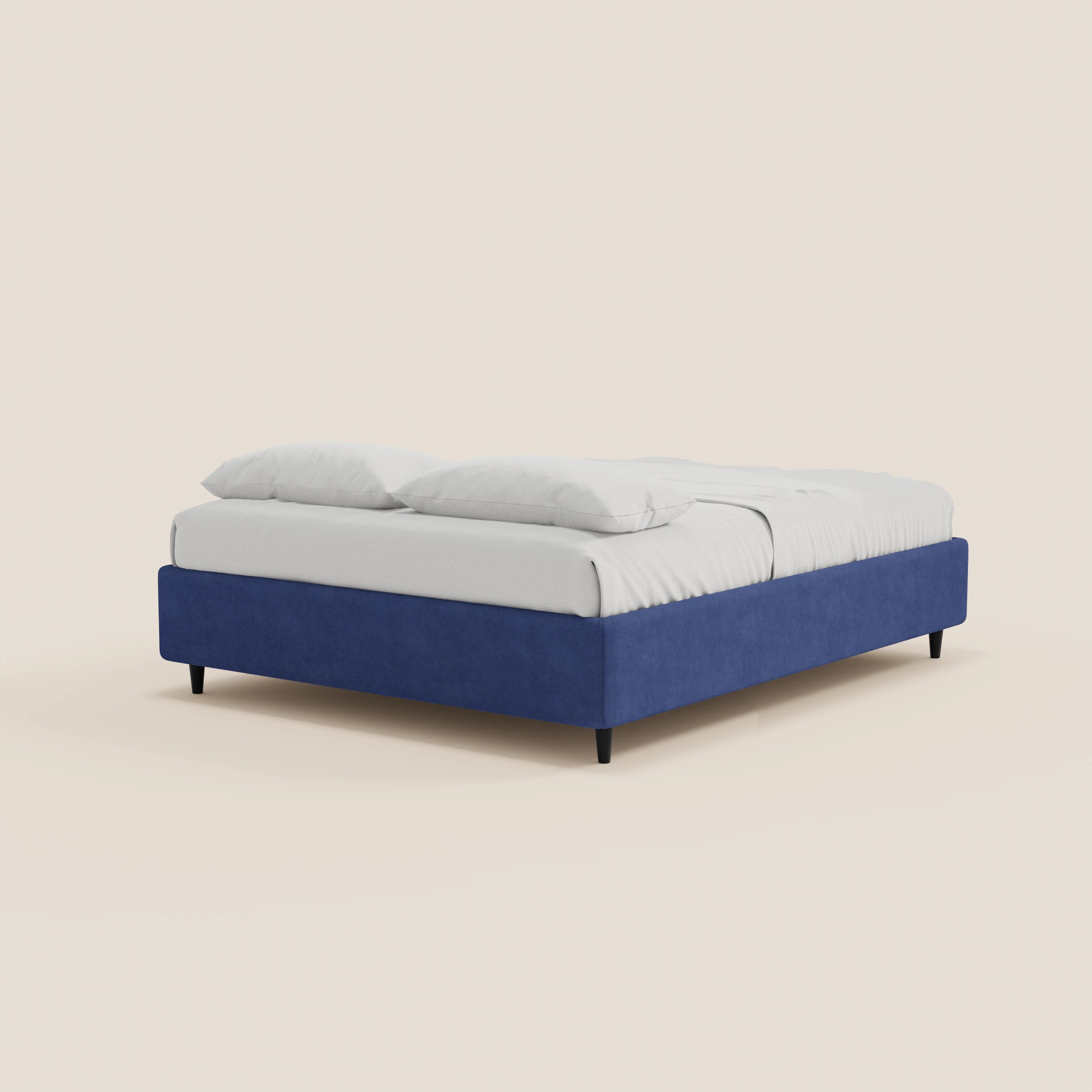 Il letto sommier imbottito ERON di Letti.store presenta una struttura rivestita in tessuto impermeabile blu intenso certificato Oeko-Tex, gambe nere, un materasso bianco e due cuscini bianchi su una biancheria da letto disposta con cura, il tutto su uno sfondo bianco sporco.