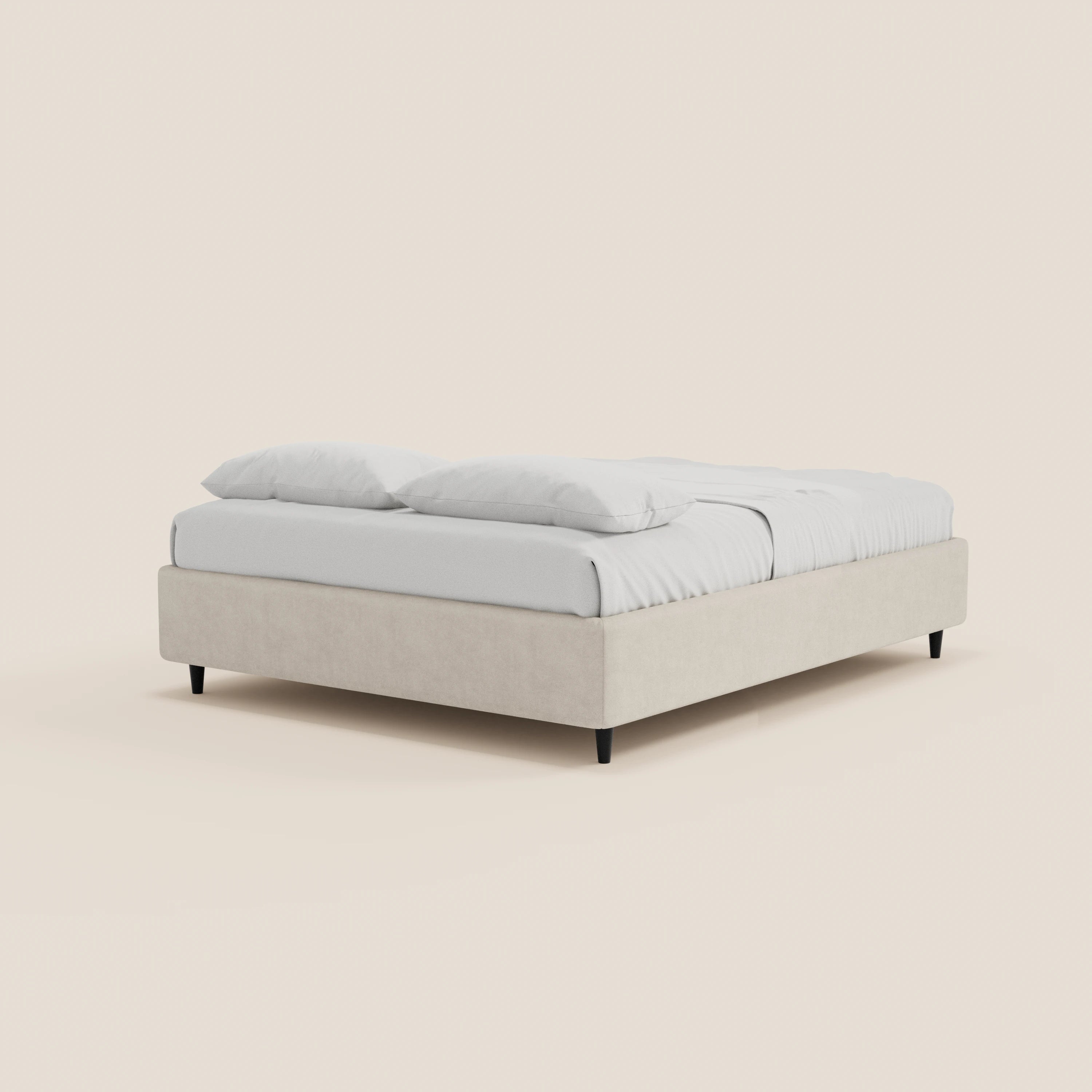 Il letto sommier ERON di Letti.store è un letto imbottito dal profilo ribassato, realizzato in tessuto beige impermeabile certificato Oeko-Tex, dotato di base contenitiva, biancheria da letto e cuscini bianchi, gambe corte nere e un design minimalista senza testiera.