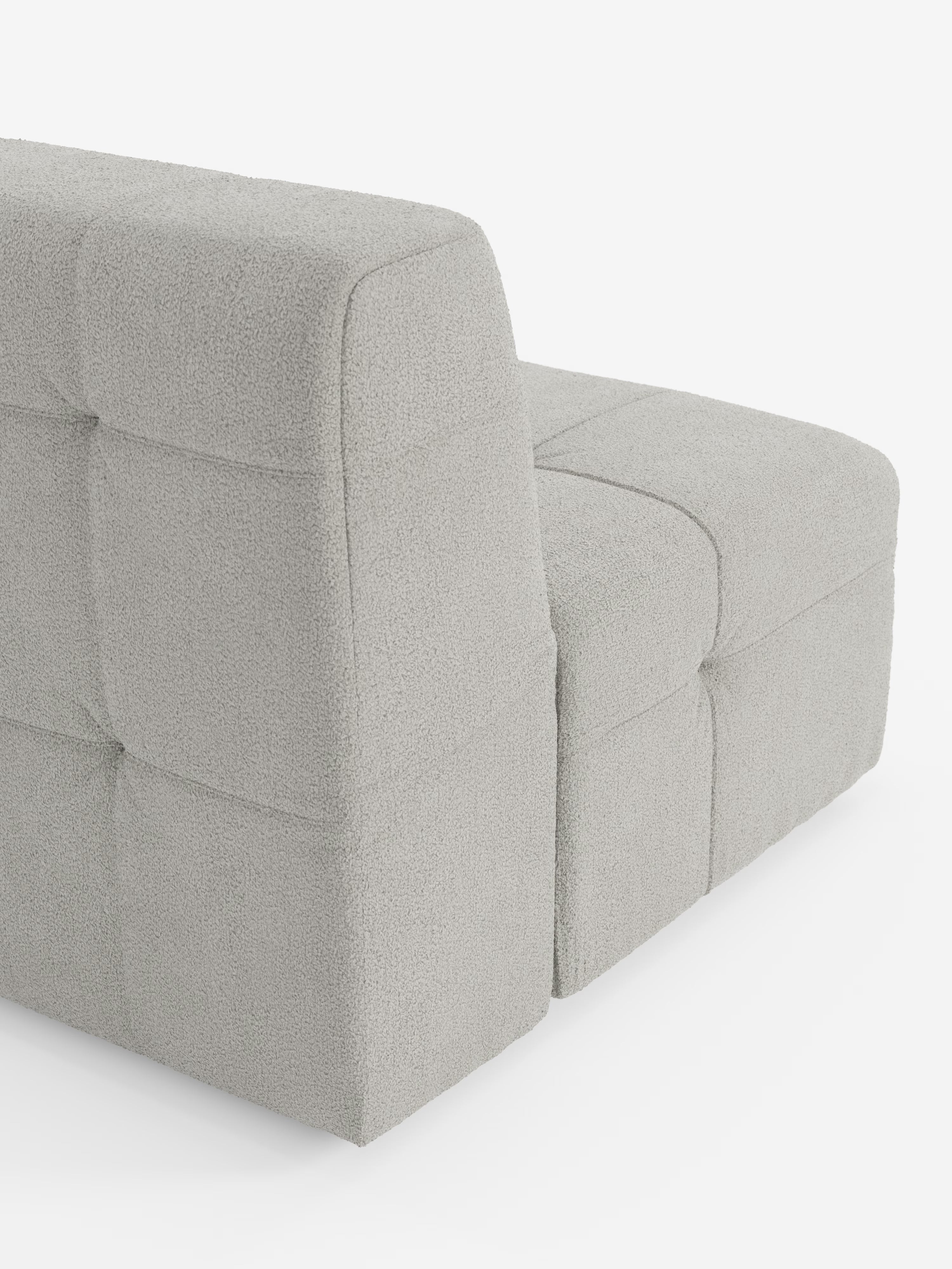 Una moderna poltrona modulare Mosaic (77 cm) di colore grigio chiaro, realizzata in tessuto bouclé T21 antimacchia di Divani.Store, è raffigurata vista da dietro. Il divano componibile presenta linee squadrate e geometriche con cuciture capitonné e senza gambe a vista, creando un’estetica minimalista che riflette la raffinata maestria artigianale del design Made in Italy.