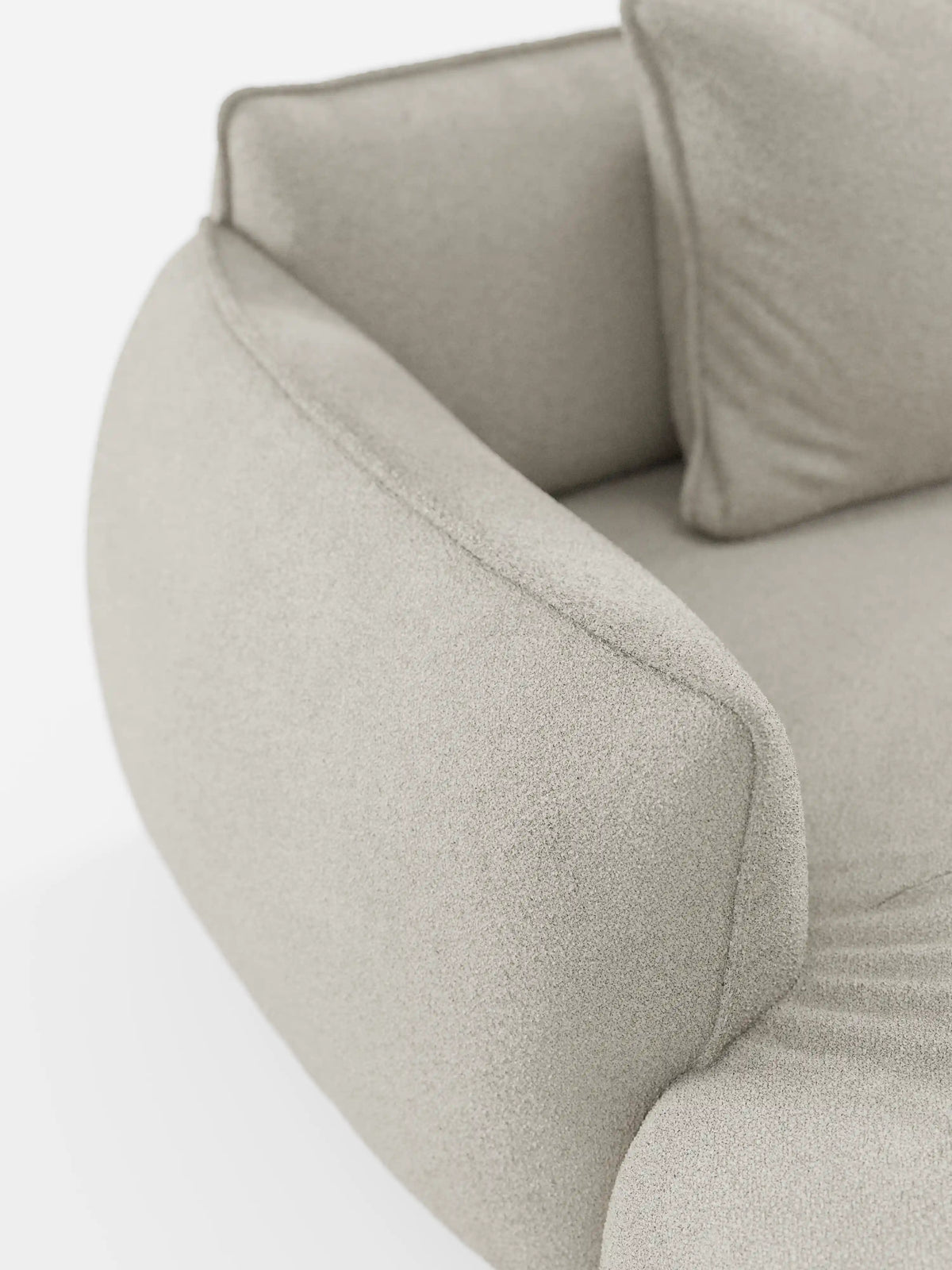 Primo piano del divano angolare panoramico componibile Nimbus con penisola e angolo in tessuto smacchiabile T33 di Divani.Store, caratterizzato da un moderno tessuto beige chiaro con una finitura morbida e testurizzata. Il bracciolo liscio e arrotondato e il morbido cuscino coordinato risaltano sullo sfondo bianco e pulito, sottolineando l’eleganza minimalista di questo divano componibile di produzione italiana.