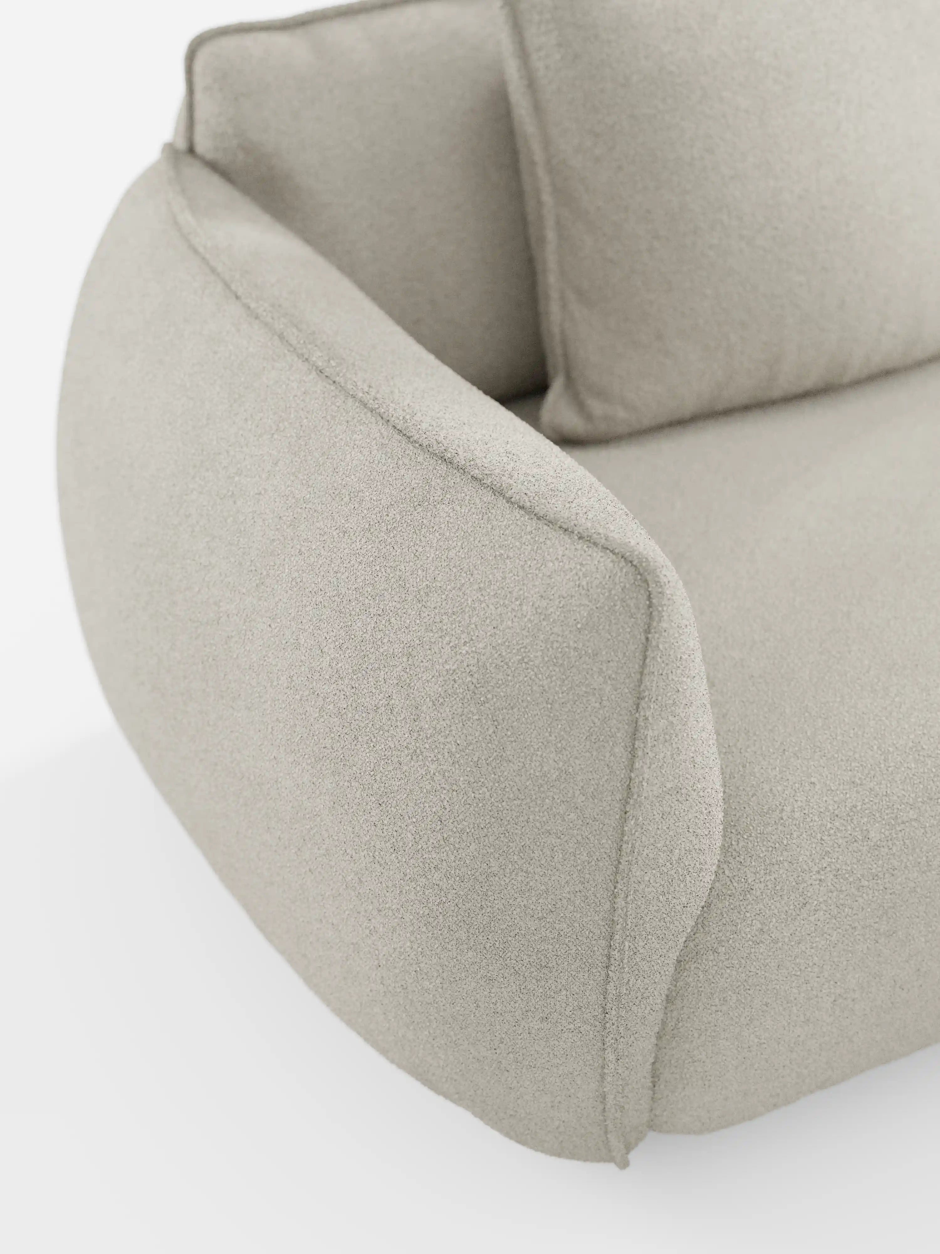Primo piano del divano modulare e componibile a 3 posti Nimbus da 250 cm di Divani.Store, rivestito in tessuto beige chiaro, sfoderabile, con finitura antimacchia effetto cotone (tessuto smacchiabile effetto cotone t33). Caratterizzato da una silhouette moderna e sinuosa con braccioli e cuscini arrotondati e morbidi, la sua trama soffice e leggermente felpata risalta sullo sfondo bianco, mettendo in risalto il design liscio e contemporaneo.