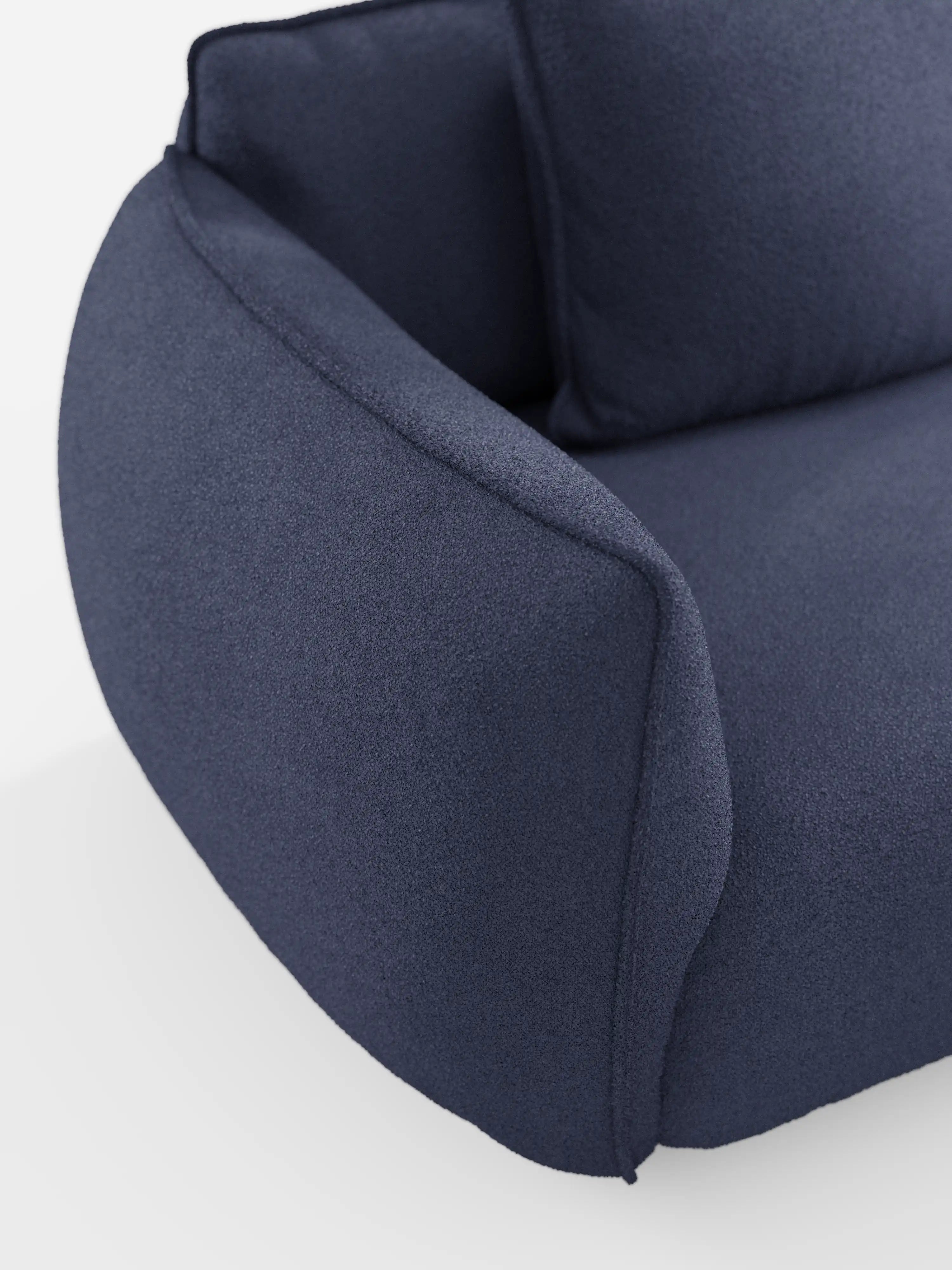 Primo piano del divano Nimbus a 3 posti, modulare e componibile, da 250 cm di Divani.Store, presentato in tessuto T33 blu scuro effetto cotone, resistente alle macchie. L’immagine mostra solo il bracciolo, la seduta e parte dello schienale, mettendo in risalto le sue curve morbide e arrotondate e i cuscini imbottiti e spessi su uno sfondo bianco. Il suo design modulare consente di creare diverse configurazioni di seduta.