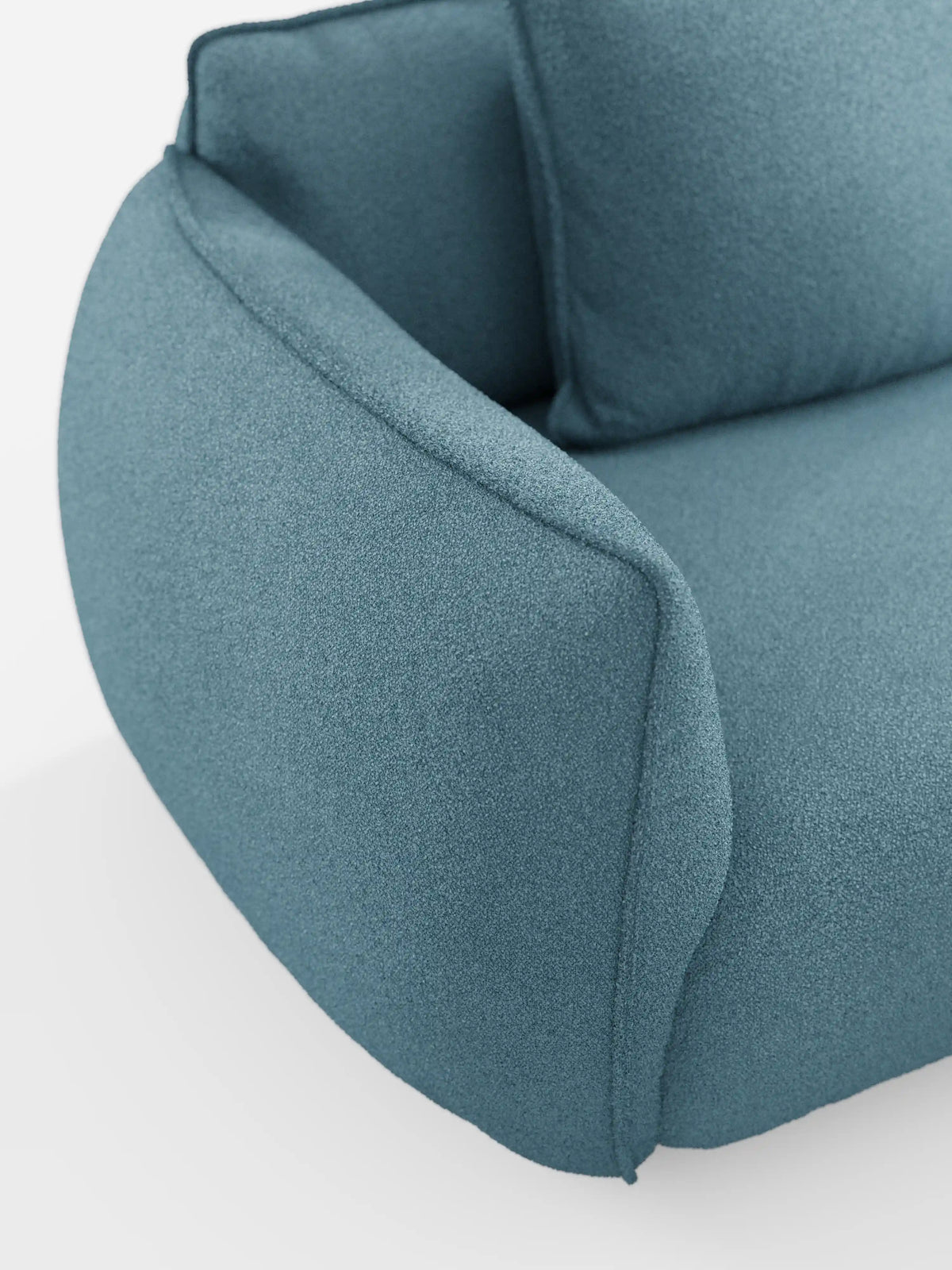 Primo piano del divano modulare e componibile a 3 posti Nimbus da 250 cm di Divani.Store, rivestito in morbido tessuto blu testurizzato smacchiabile effetto cotone T33. Il design si caratterizza per i bordi arrotondati, i braccioli spessi e i soffici cuscini dello schienale, il tutto su uno sfondo bianco a tinta unita.