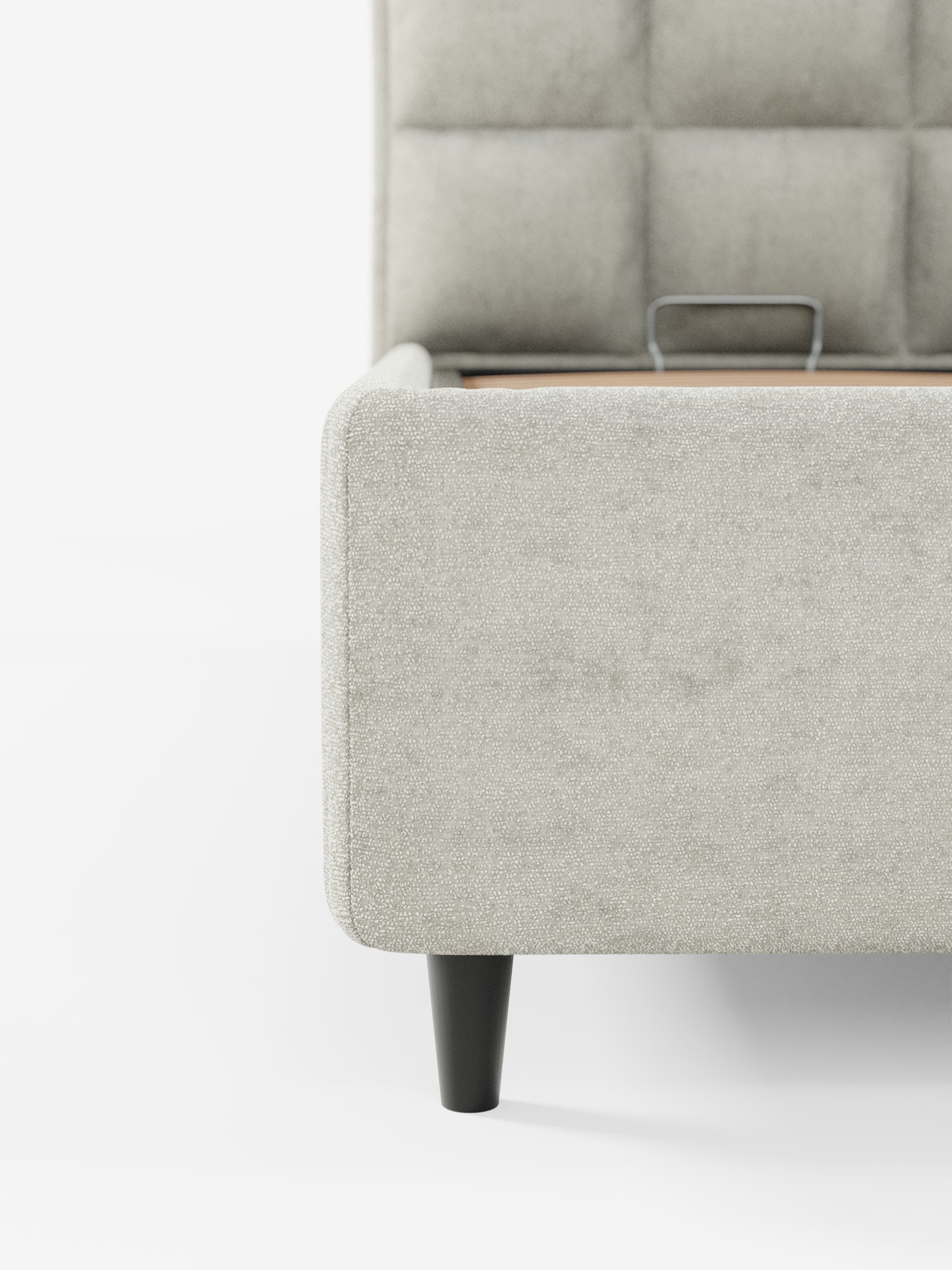 Primo piano del letto imbottito AURO grigio chiaro con contenitore e testiera alta capitonné in ciniglia Oeko-Tex® di Letti.store, caratterizzato da una testiera alta capitonné, angoli arrotondati e gambe in legno nero. L'immagine mostra un lato del letto su uno sfondo bianco a tinta unita.