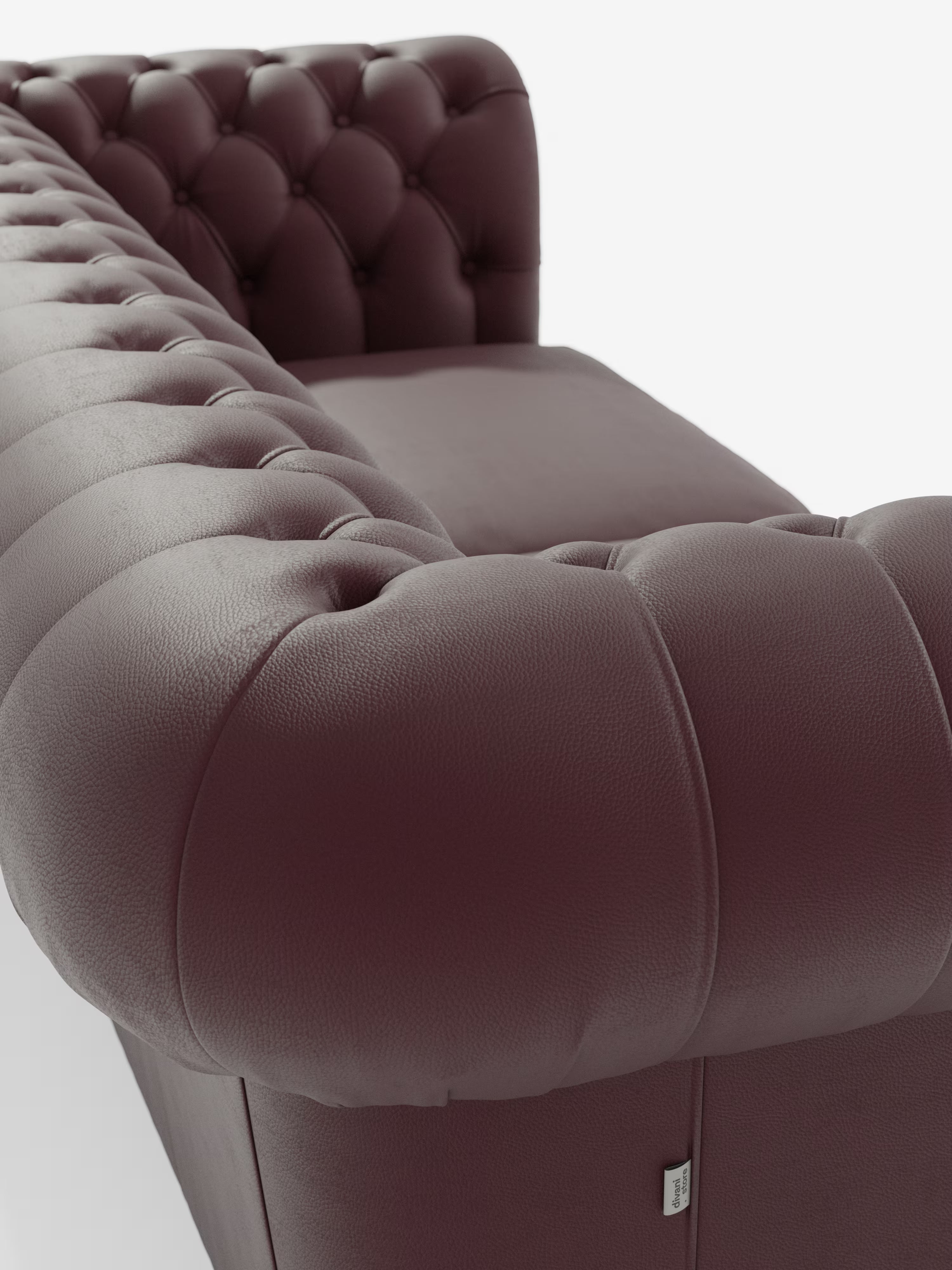 Primo piano del Chester – Divano Chesterfield in vera pelle spessorata a 2 e 3 posti di Divani.Store, caratterizzato da un rivestimento in pelle trapuntata color bordeaux intenso con i classici dettagli del design Chesterfield, tra cui braccioli ricurvi, bottoni decorativi, texture morbida e una finitura liscia che risalta sullo sfondo bianco.