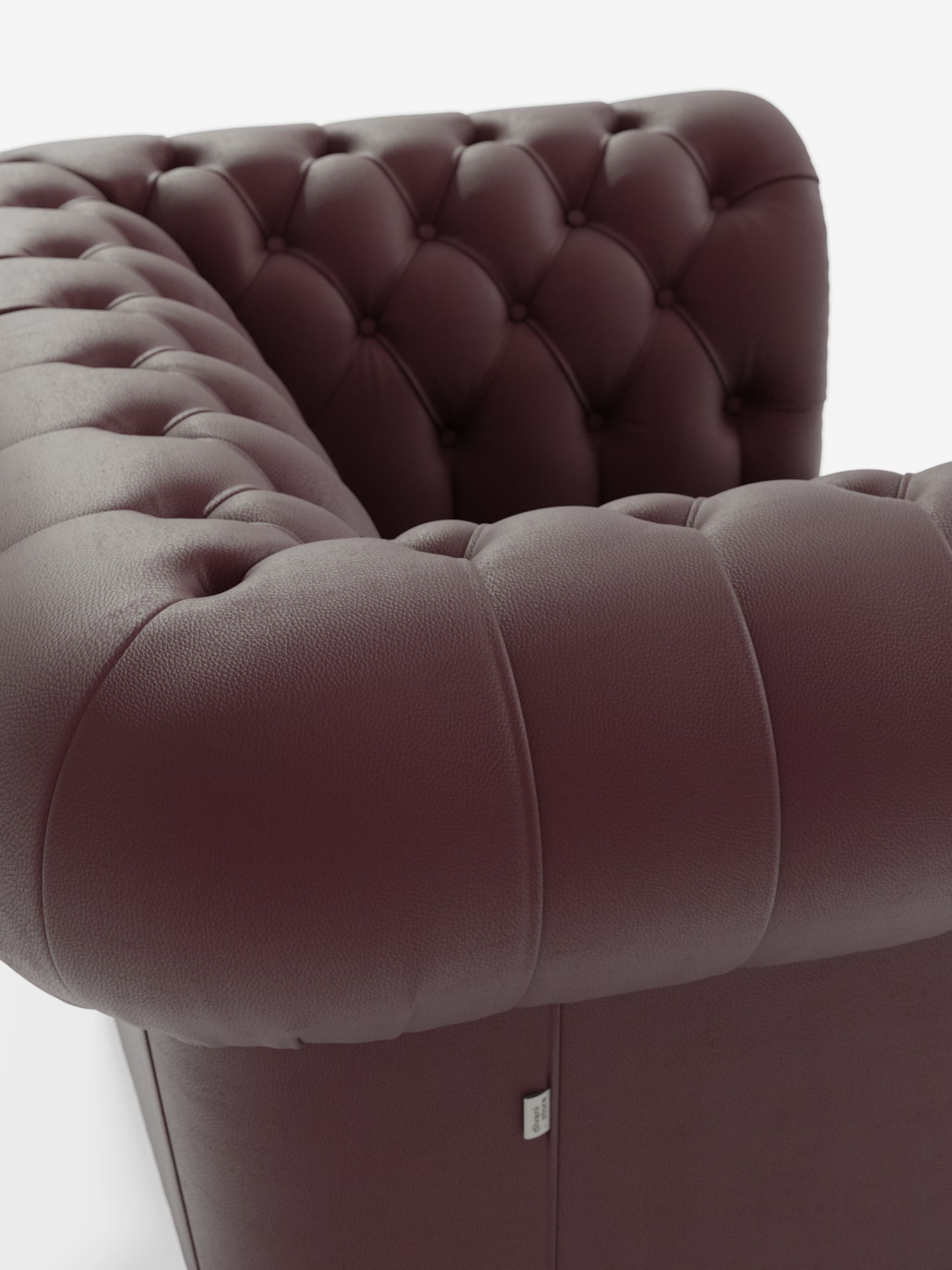 Primo piano della poltrona Chester in vera pelle spessorata con capitonné artigianale di Divani.Store, caratterizzata da una ricca pelle color bordeaux scuro con profondi bottoni capitonné — realizzati nel classico stile capitonné — sui braccioli e sullo schienale. L'immagine ne mette in risalto la morbida consistenza e il lussuoso rivestimento, ripresa dall'angolo superiore su uno sfondo bianco a tinta unita.