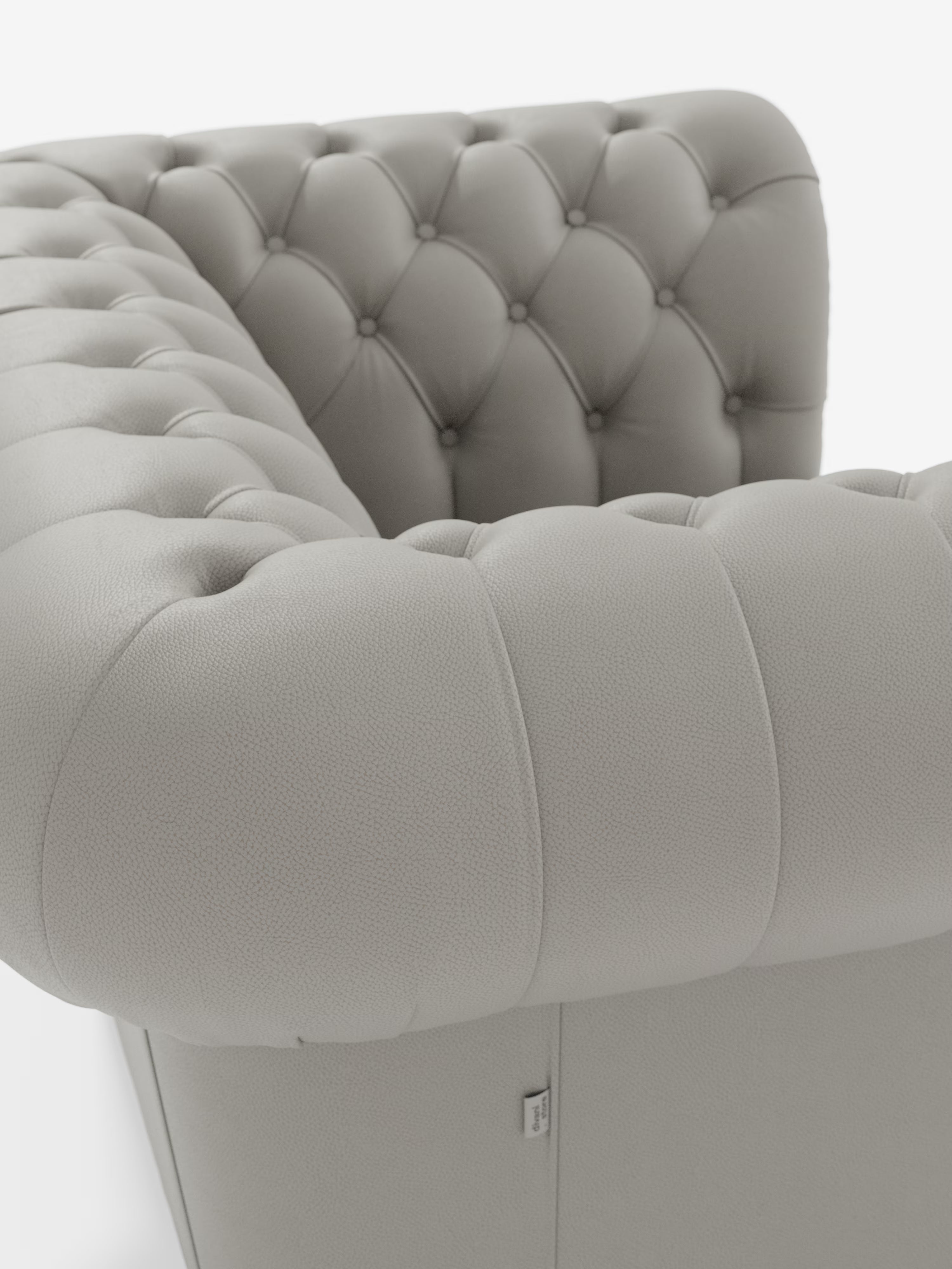 Primo piano della poltrona Chester in vera pelle spessorata con capitonné artigianale di Divani.Store, qui raffigurata nella finitura grigio chiaro. La poltrona presenta eleganti dettagli capitonné realizzati a mano che le conferiscono un aspetto intramontabile, con morbidi braccioli arrotondati e rivestimento in vera pelle finemente granulata. Sullo sfondo bianco, ogni raffinata caratteristica di questa poltrona classica viene messa magnificamente in risalto.