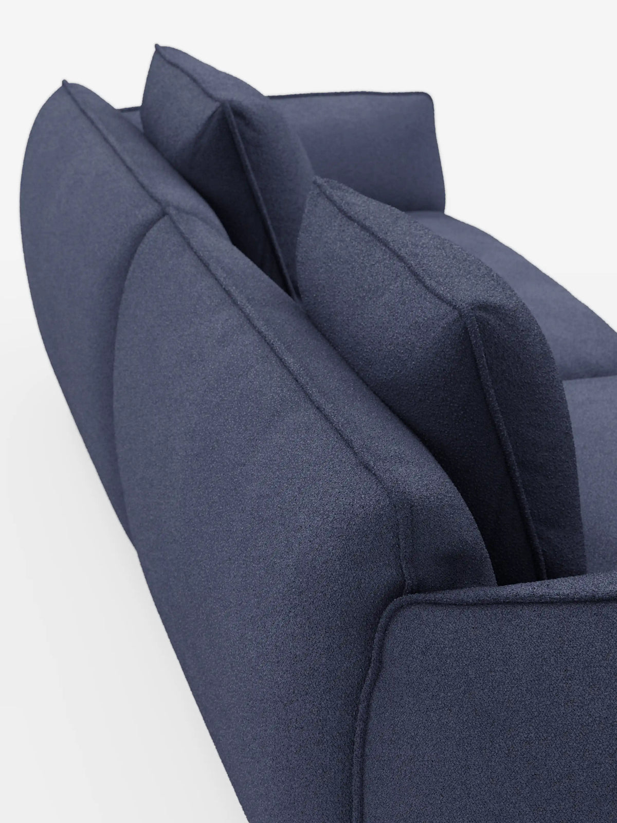 Una vista ravvicinata e obliqua del divano Nimbus a 3 posti, modulare e componibile da 250 cm di Divani.Store, rivestito in tessuto effetto cotone blu scuro antimacchia (t33), con due cuscini dello schienale e un design pulito e minimalista, su sfondo bianco.
