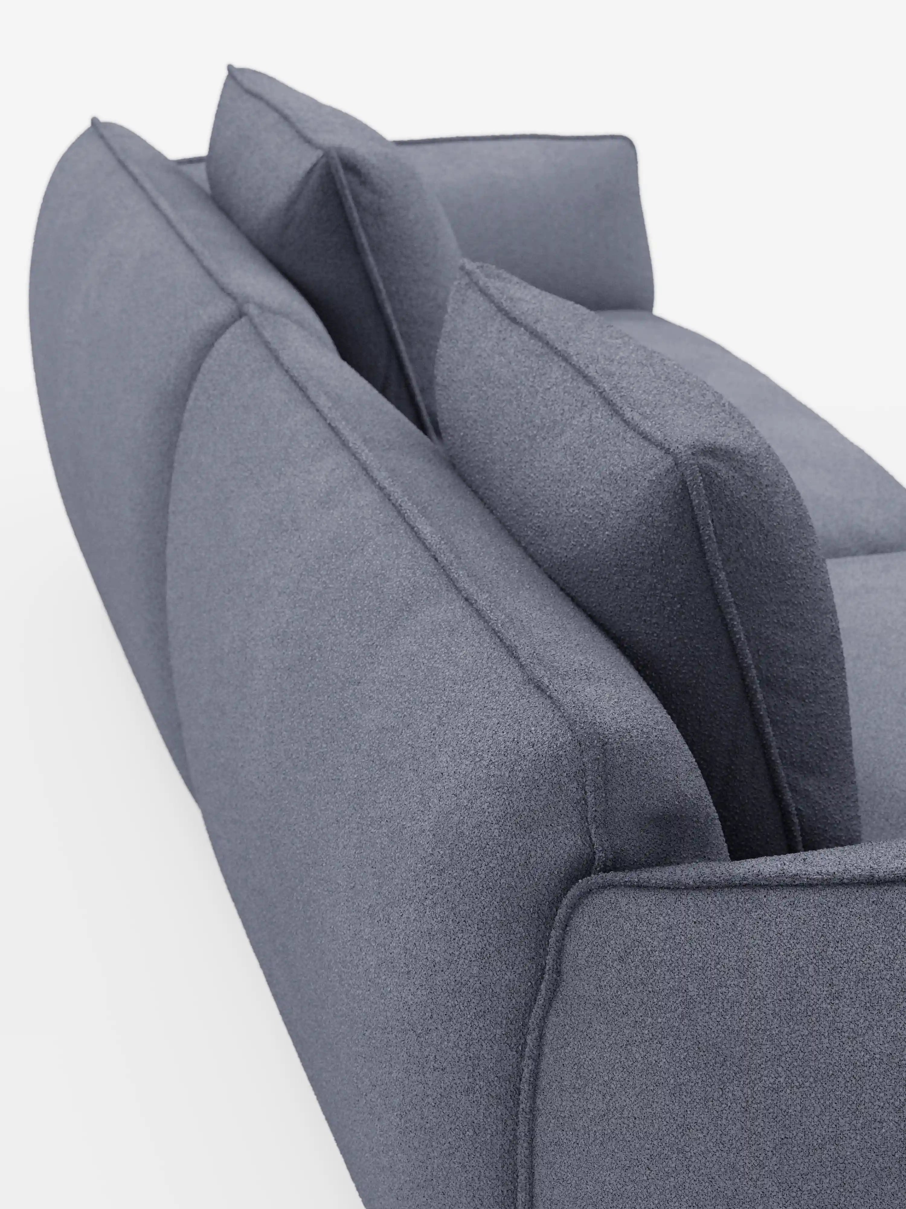 Primo piano della parte posteriore del divano modulare e componibile a 3 posti Nimbus di Divani.Store, lungo 250 cm, rivestito in tessuto sfoderabile e antimacchia effetto cotone t33 in grigio moderno, dotato di due cuscini dello schienale e due ampi cuscini di seduta. Su uno sfondo bianco a tinta unita, l’immagine mette in risalto la morbida trama del tessuto e le linee pulite e scolpite del divano.