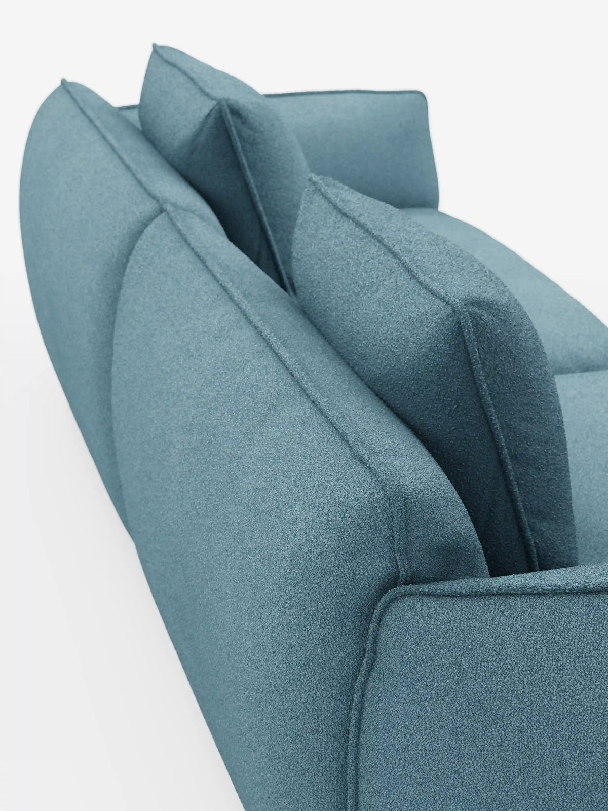Una vista ravvicinata e angolata del divano modulare e componibile a 3 posti Nimbus di Divani.Store, lungo 250 cm, rivestito in morbido tessuto color verde acqua smacchiabile effetto cotone T33, con due cuscini dello schienale e due cuscini della seduta. Le linee pulite e morbide del divano risaltano sullo sfondo bianco a tinta unita.