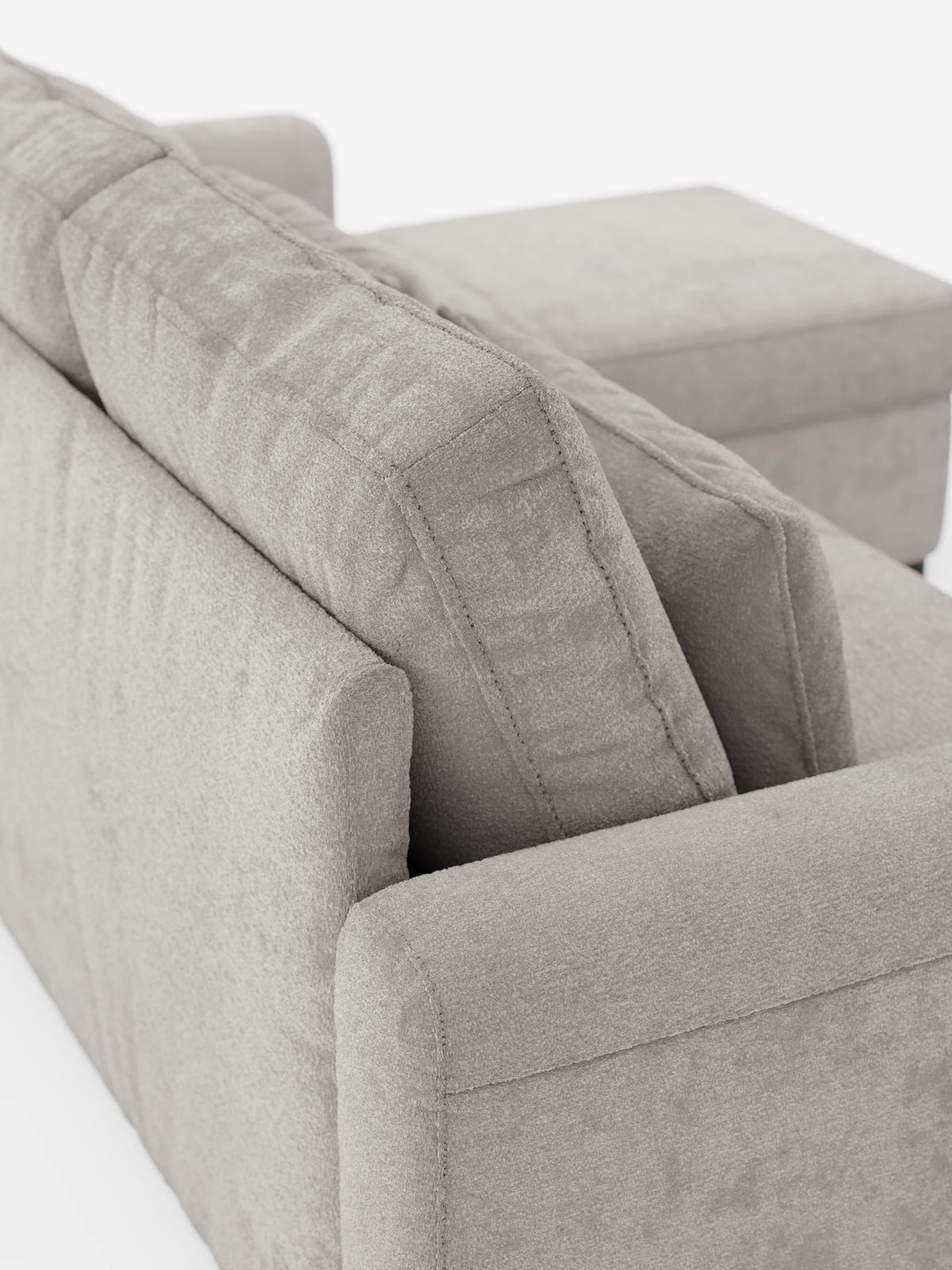 Vista laterale dall'alto di un divano letto Ottaviano grigio chiaro con letto estraibile - penisola reversibile e contenitore in tessuto materico smacchiabile, caratterizzato da cuscini dello schienale spessi, braccioli squadrati e una chaise longue integrata.
