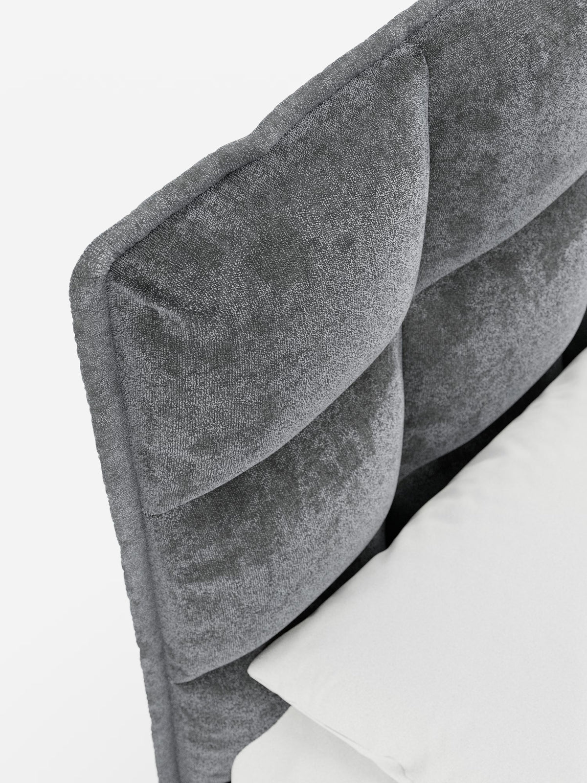 Primo piano del letto imbottito AURO con contenitore e testiera capitonné alta in ciniglia Oeko-Tex® di Letti.store, che mette in risalto la testiera grigia trapuntata con una morbida finitura vellutata in ciniglia e eleganti dettagli capitonné. La testiera alta presenta ampie sezioni rettangolari imbottite che richiamano lo stile classico. Un cuscino bianco e un materasso fanno capolino in basso a destra su uno sfondo bianco a tinta unita, sottolineando il fascino raffinato di questo letto imbottito con