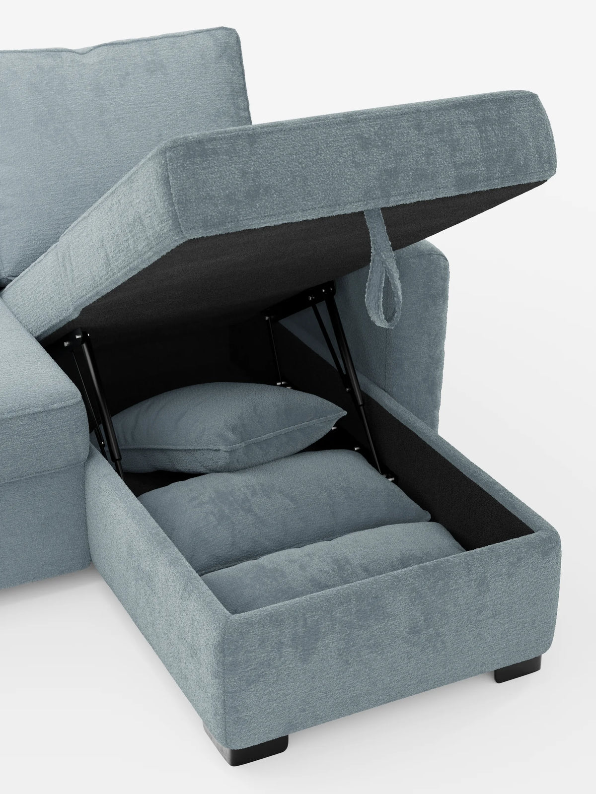 Un divano letto Ottaviano azzurro con letto estraibile - penisola reversibile e contenitore in tessuto materico smacchiabile, con la chaise longue sollevata per rivelare un vano contenitore che ospita due cuscini coordinati su una base scura.