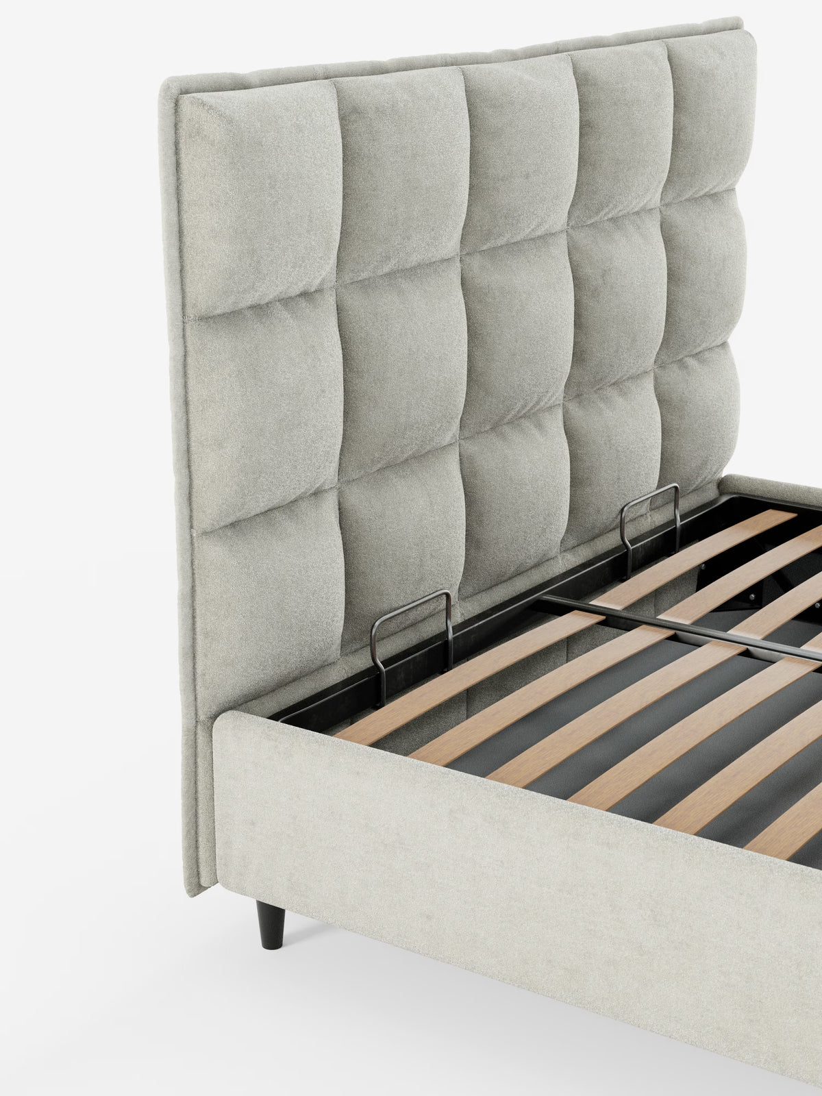 Un primo piano dettagliato del letto imbottito AURO con contenitore e testiera alta capitonné in ciniglia Oeko-Tex® di Letti.store, caratterizzato da una testiera alta capitonné rivestita in tessuto ciniglia grigio chiaro. Sono visibili le doghe in legno e i supporti in metallo nero della base del letto contenitore, con il letto appoggiato su gambe corte e angolate di colore nero su uno sfondo bianco a tinta unita.