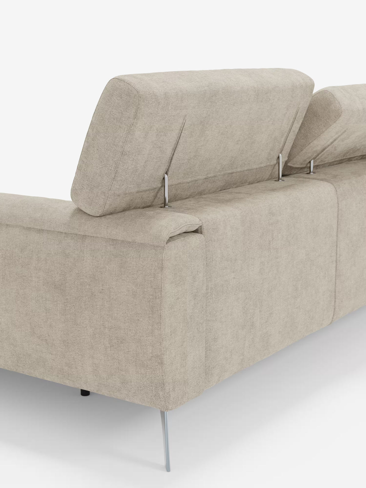 Un primo piano del divano angolare Caravaggio con penisola e sedute scorrevoli in tessuto smacchiabile T31 di Divani.Store, un moderno divano in tessuto beige con eleganti gambe in metallo e due poggiatesta regolabili, ripreso dal retro. Dotato di sedute scorrevoli per un comfort personalizzabile, lo sfondo bianco a tinta unita mette in risalto le linee pulite e il design minimalista del divano.