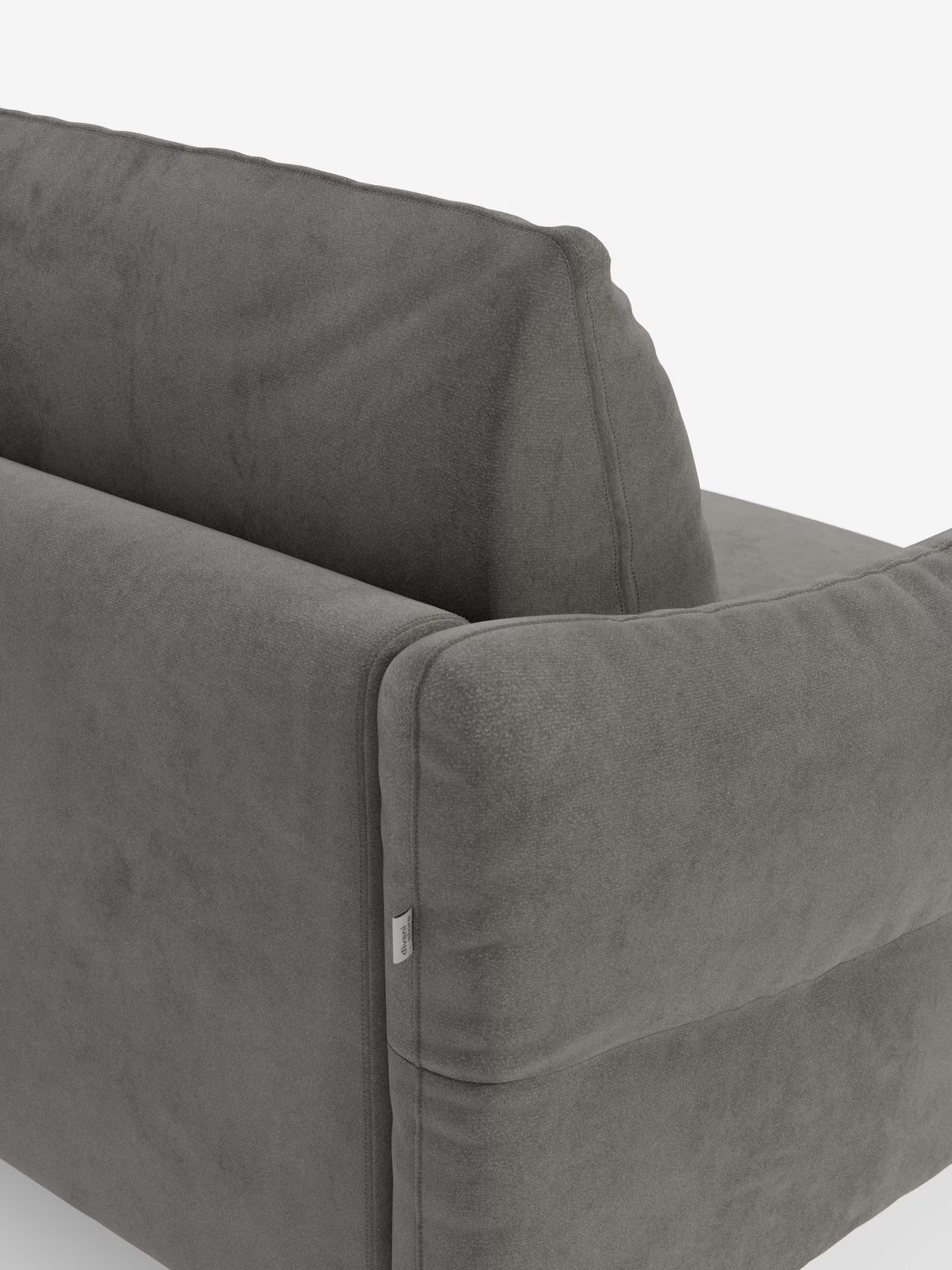 Primo piano dello schienale e del bracciolo di un divano letto Dalia grigio di Divani.Store, ripreso su sfondo bianco. L'immagine mette in risalto il rivestimento in morbido tessuto vellutino moderno T30, resistente alle macchie, con la sua trama particolare, i semplici dettagli di cucitura e una piccola etichetta in tessuto applicata al bracciolo.
