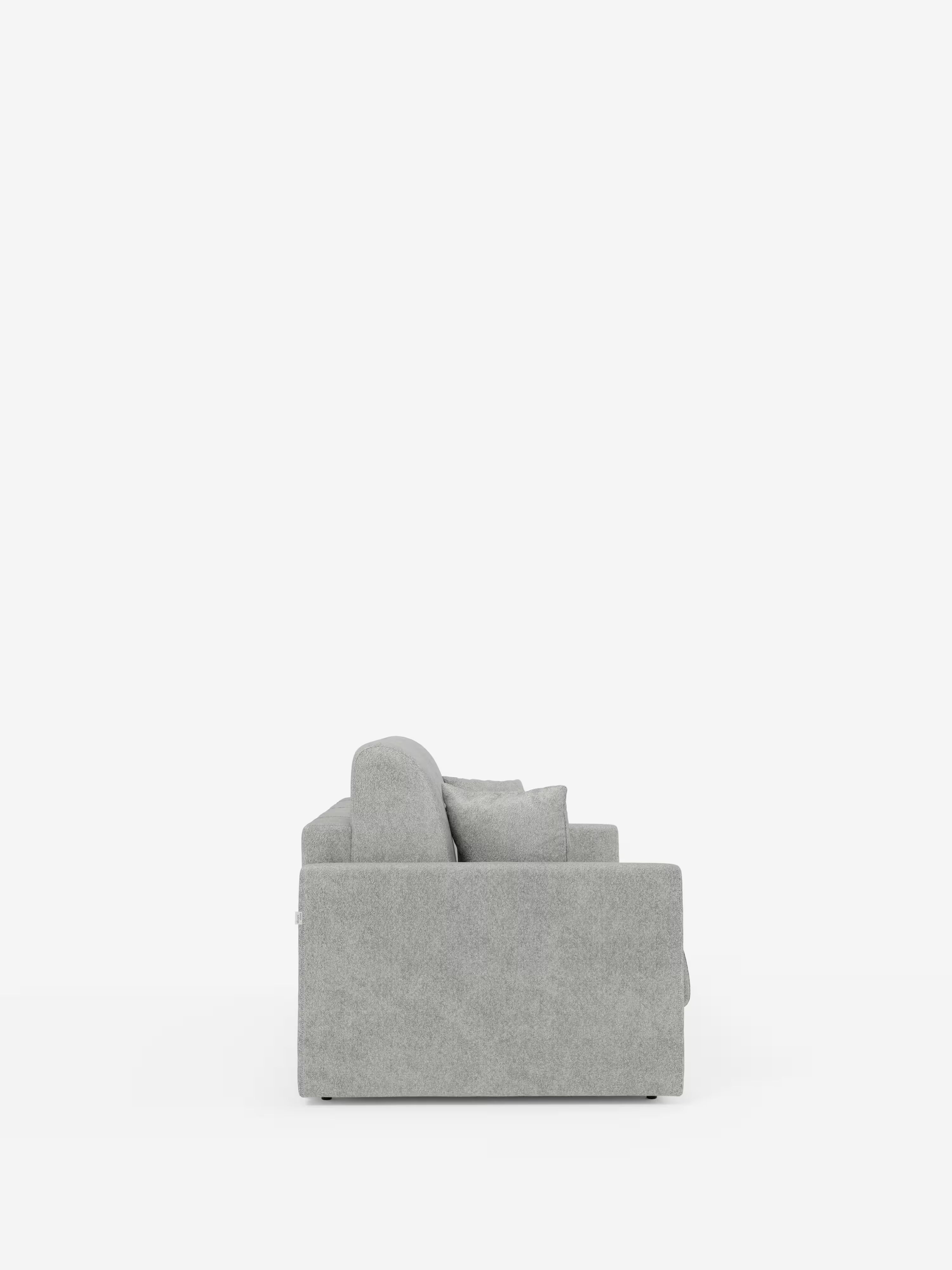 Una vista di profilo del divano letto Tommy Divano a 2 e 3 posti matrimoniale di Divani.Store, rivestito in tessuto T33 effetto cotone grigio chiaro e resistente alle macchie, con fodere completamente sfoderabili, è raffigurato su uno sfondo bianco pulito. Questo divano dal design contemporaneo presenta una struttura rettangolare, uno schienale confortevole con un cuscino decorativo abbinato e braccioli semplici e lineari, per un design minimalista e moderno.
