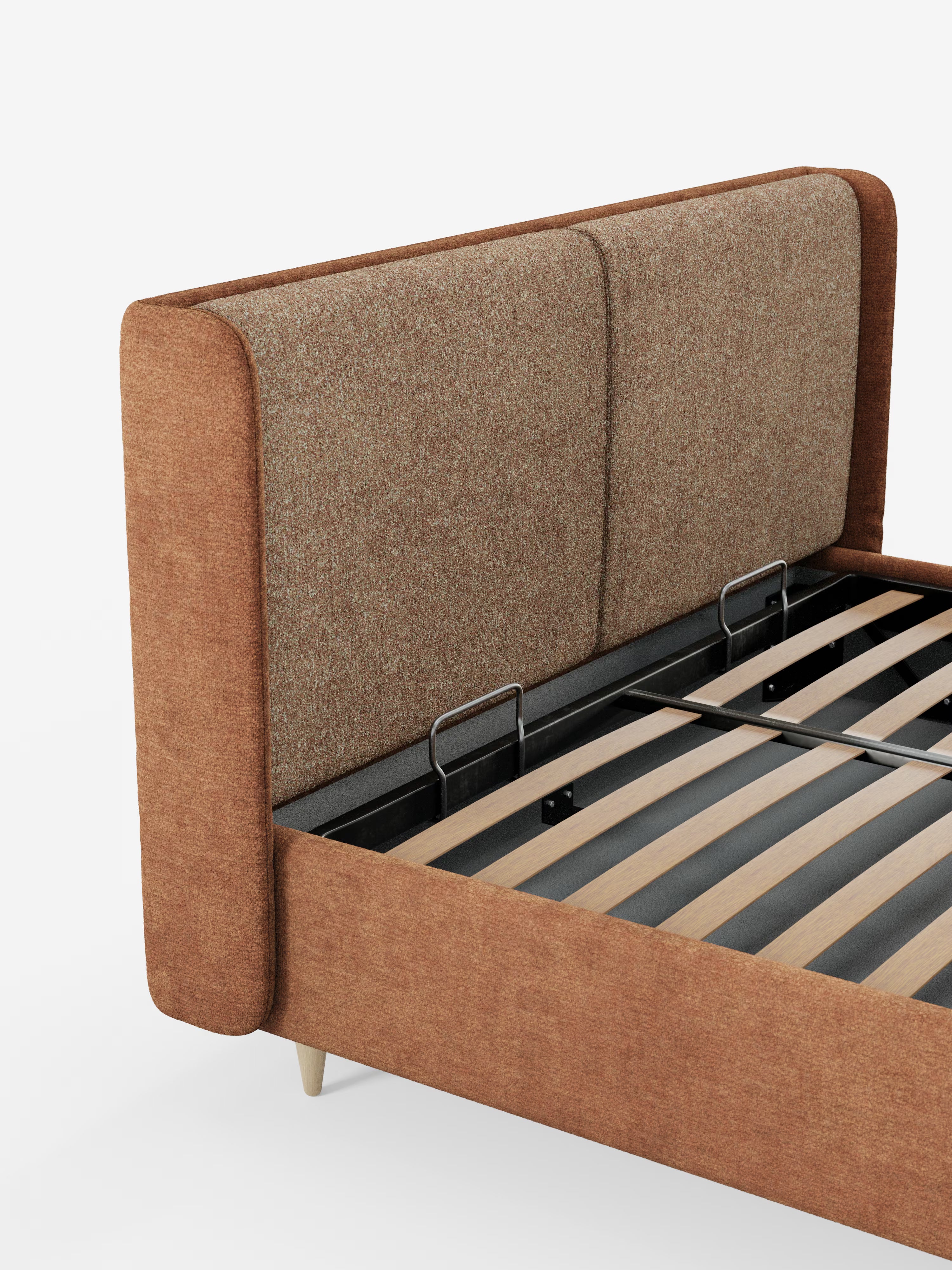 Un primo piano del letto imbottito bicolore VALKIRIA con contenitore di Letti.store mette in risalto una struttura rivestita in tessuto marrone e una testiera imbottita avvolgente, dalla forma curva e dalla trama in rilievo, completa di cuscini schienali. Il design moderno presenta doghe in legno chiaro e supporti in metallo nero, con alcune parti della struttura e delle gambe visibili su uno sfondo bianco.