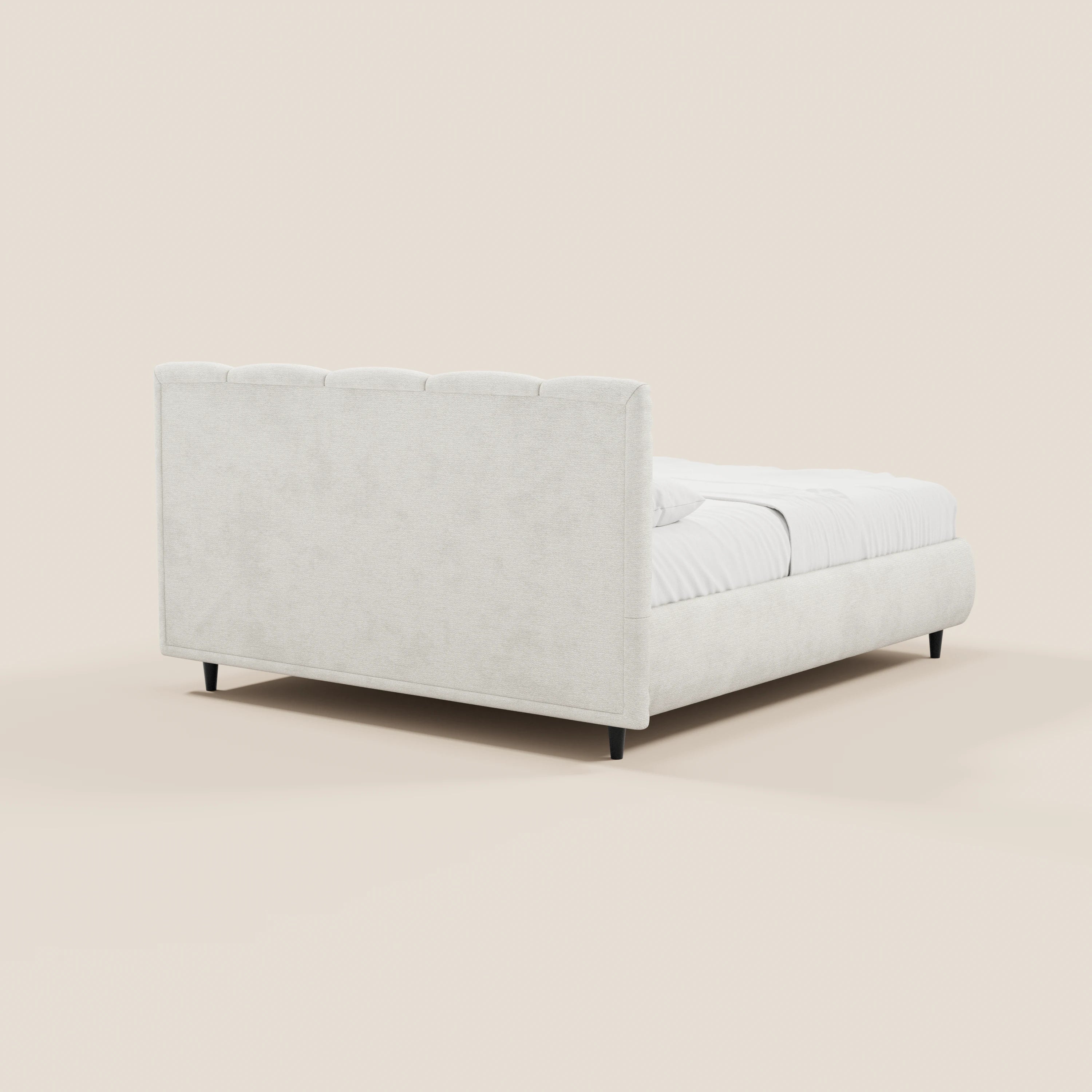 Il letto imbottito ARKAM di Letti.store presenta una testiera alta con cuciture verticali e una pediera abbinata in tessuto beige chiaro certificato Oeko-Tex®, gambe basse scure, biancheria da letto bianca e uno sfondo a tinta unita color crema chiaro.