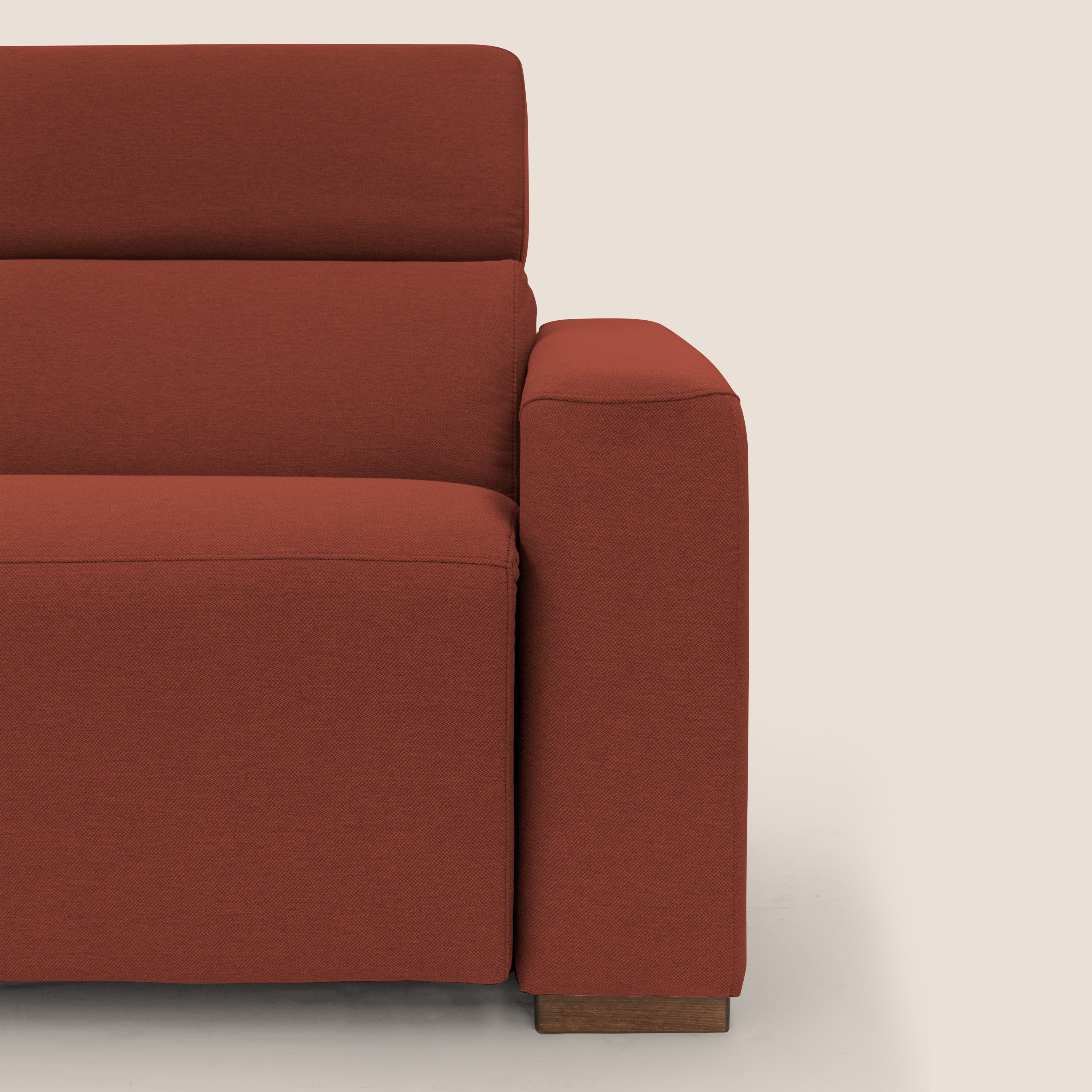 Primo piano del divano letto Poseidon + relax elettrico di Divani.Store, in tessuto impermeabile antimacchia rosso T05, con ampio bracciolo, linee pulite e base in legno su sfondo beige chiaro. È visibile solo la metà destra.