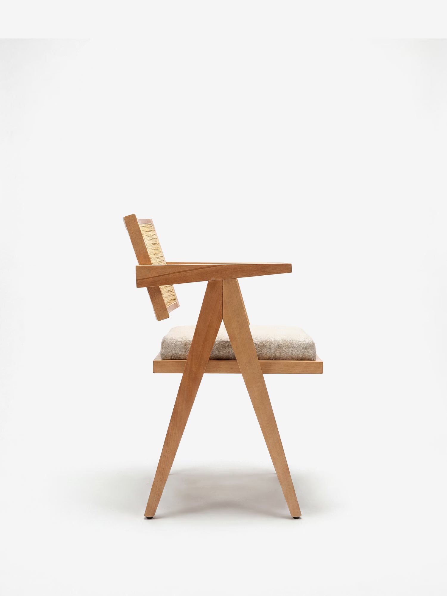 La sedia Antea con braccioli in rovere di Divani.Store, qui raffigurata in vista laterale, presenta una struttura a forma di A, uno schienale in rattan e una seduta imbottita in misto cotone. La sua texture in legno naturale risalta sullo sfondo bianco.