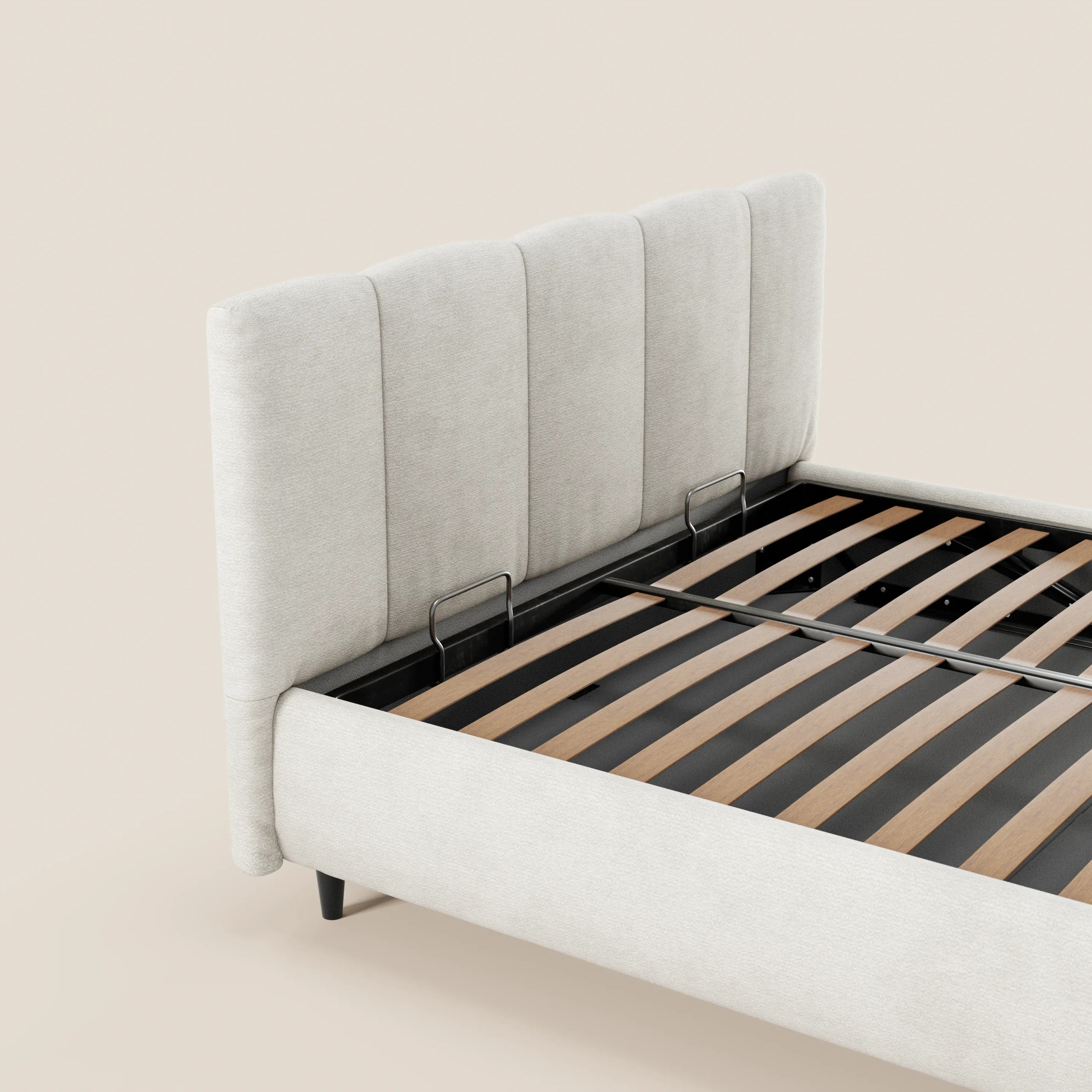 Il letto imbottito ARKAM di Letti.store presenta una testiera alta, rivestita in tessuto Oeko-Tex® a pannelli verticali, e supporti in metallo nero con doghe in legno. Il suo design shabby chic risalta sullo sfondo beige chiaro; del letto è visibile solo una parte.