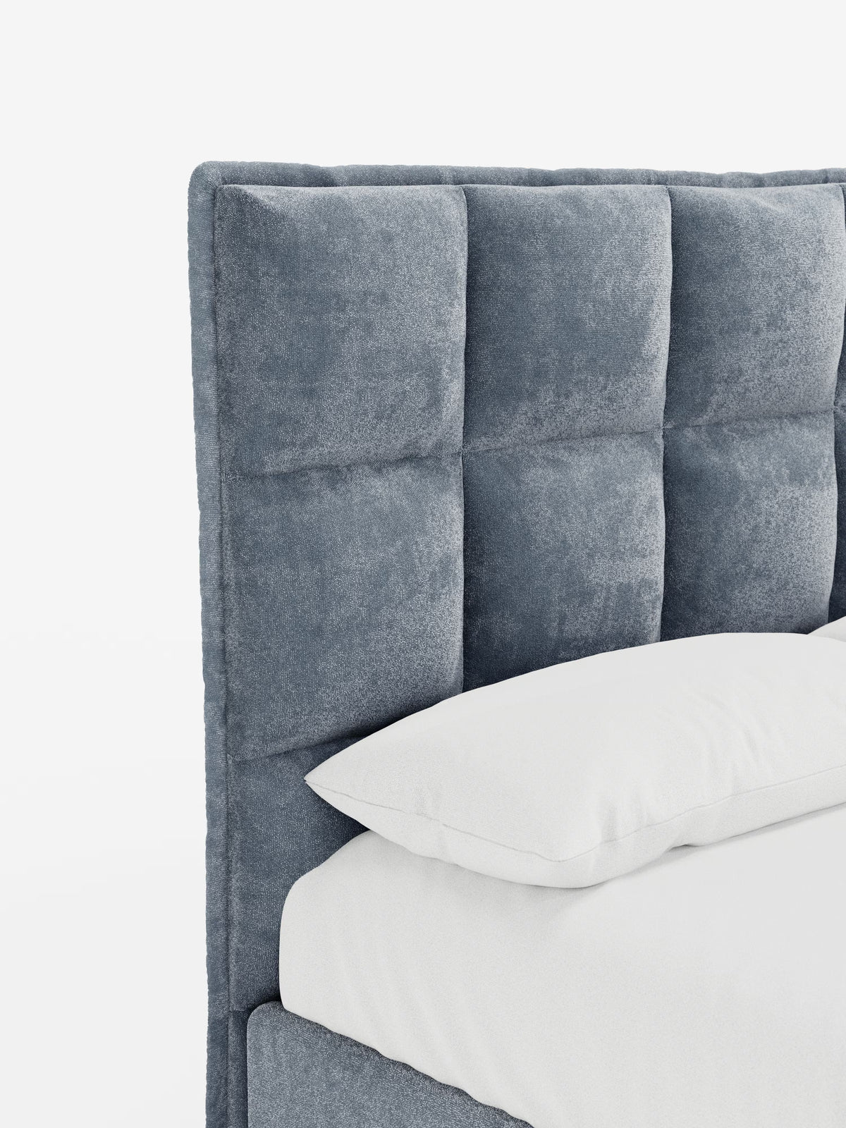 Un primo piano del letto imbottito con contenitore AURO di Letti.store mette in risalto la sua alta testiera capitonné, rivestita in morbido e soffice tessuto ciniglia grigio certificato Oeko-Tex®. Le sezioni quadrate trapuntate della testiera offrono una rivisitazione in chiave moderna del design classico. Un cuscino bianco poggia sul materasso, in perfetta armonia con la tonalità grigia della testiera. Lo sfondo è bianco a tinta unita.
