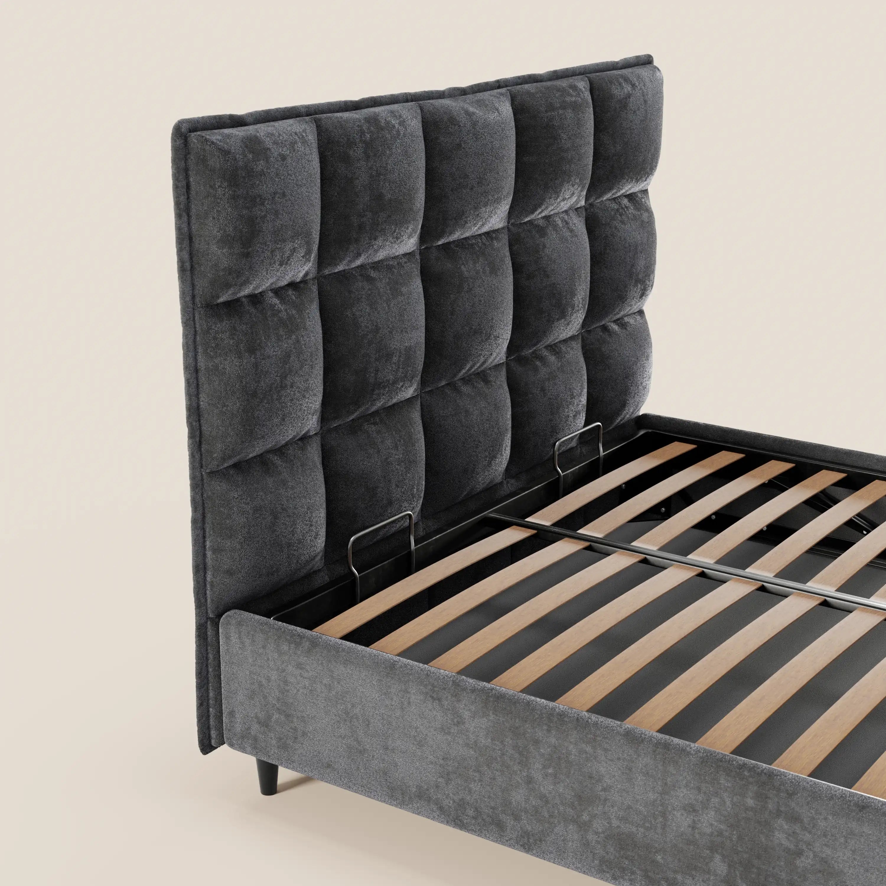 Il letto imbottito AURO di Letti.store presenta una testiera alta capitonné in ciniglia grigio scuro certificata Oeko-Tex®, doghe in legno e gambe nere. Nella foto, senza materasso né biancheria da letto, risalta su uno sfondo chiaro e semplice.