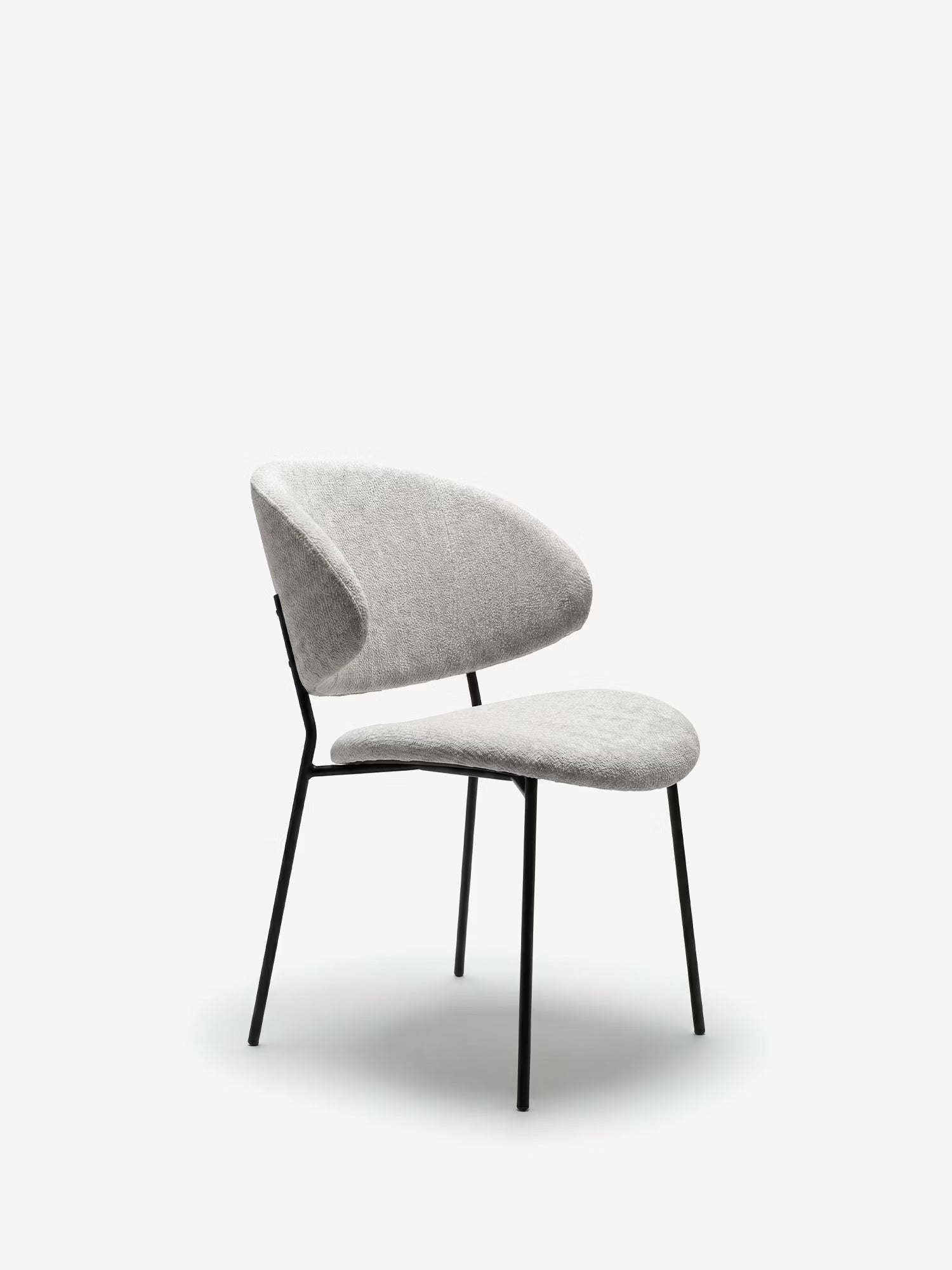 La sedia Bruma di Divani.Store, realizzata in elegante tessuto goffrato con gambe in metallo nero, presenta un design minimalista e uno schienale avvolgente, perfetta per gli ambienti moderni grazie al suo look contemporaneo ed essenziale.