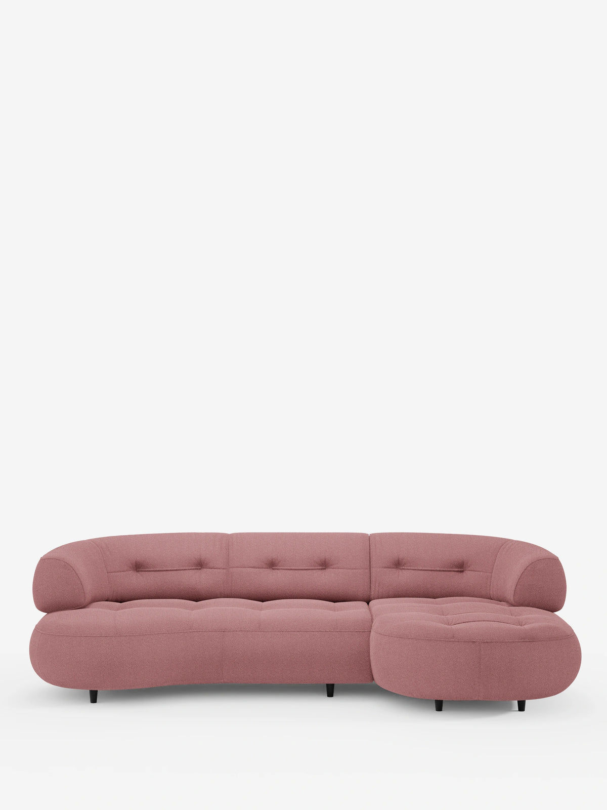 Un divano angolare “Croissant” color rosa polveroso, dal design a forma di fagiolo, con schienali scorrevoli in morbido tessuto effetto cotone smacchiabile T33, dai bordi arrotondati, cuscini trapuntati e gambe basse nere su uno sfondo bianco a tinta unita.