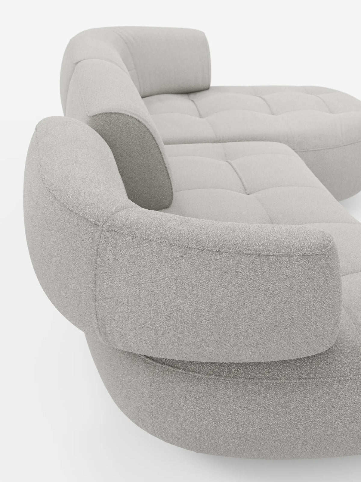Un divano angolare Croissant dalle linee curve, di colore grigio chiaro, dal design a forma di fagiolo e con schienali regolabili, rivestito in morbido tessuto effetto cotone lavabile T33, su uno sfondo bianco a tinta unita.