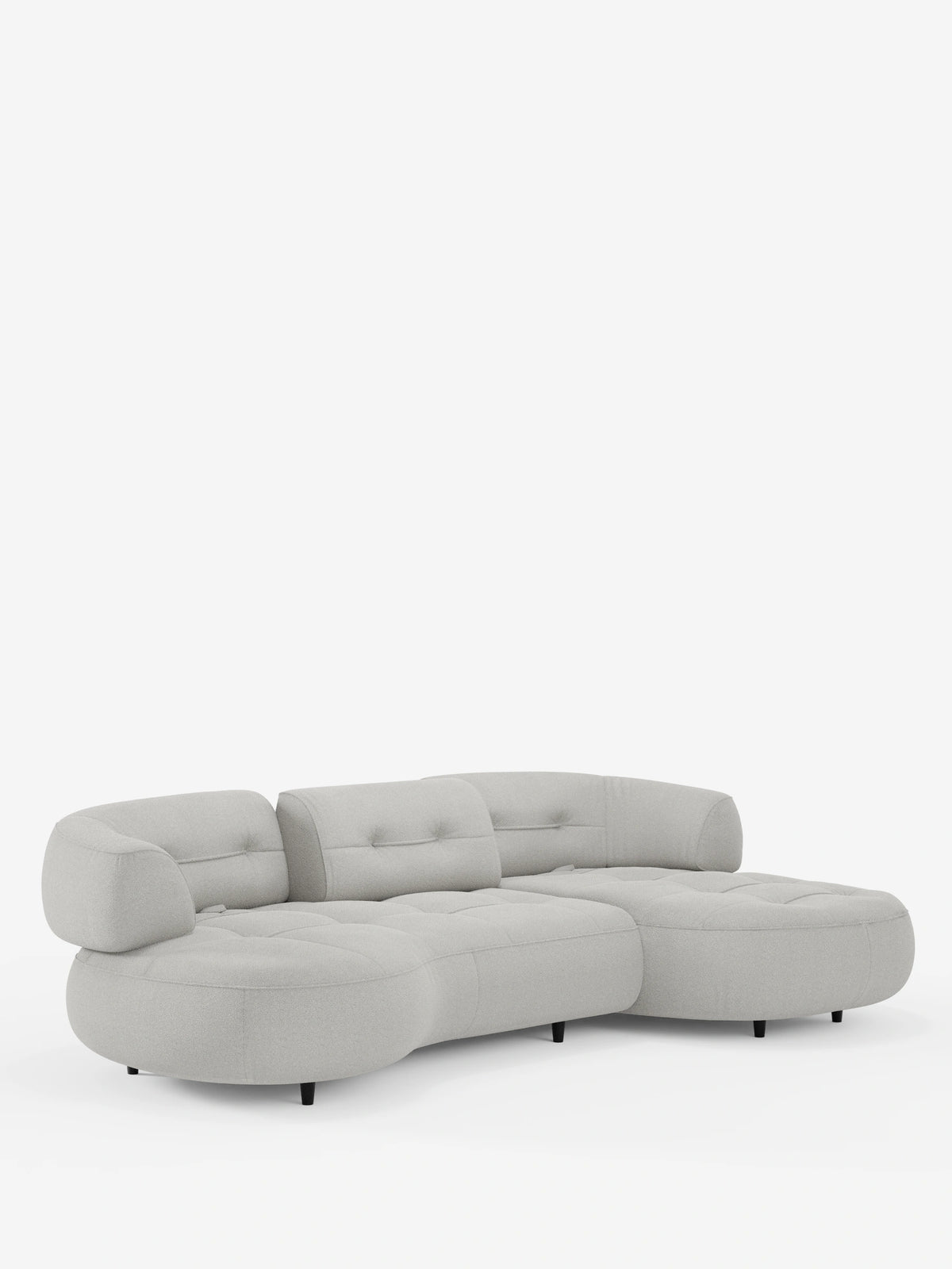 Un divano angolare “Croissant” di colore grigio chiaro, dal design a forma di fagiolo, con schienali scorrevoli in morbido tessuto effetto cotone smacchiabile T33, cuscini trapuntati, profilo ribassato, giunti meccanici a vista e piccole gambe scure.