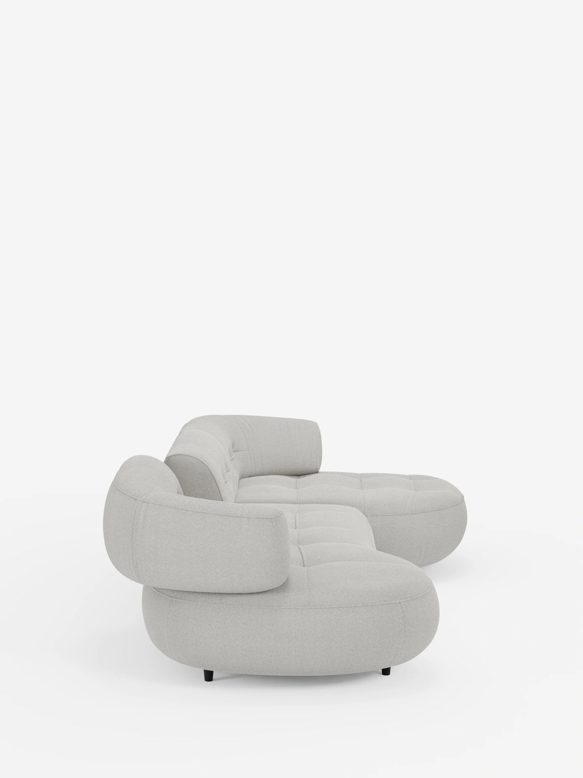 Un divano angolare “Croissant” di colore grigio chiaro, dal design a forma di fagiolo e con schienali scorrevoli in morbido tessuto effetto cotone lavabile: divano componibile T33 con trapuntatura profonda, schienali mobili e piedini scuri su sfondo bianco.