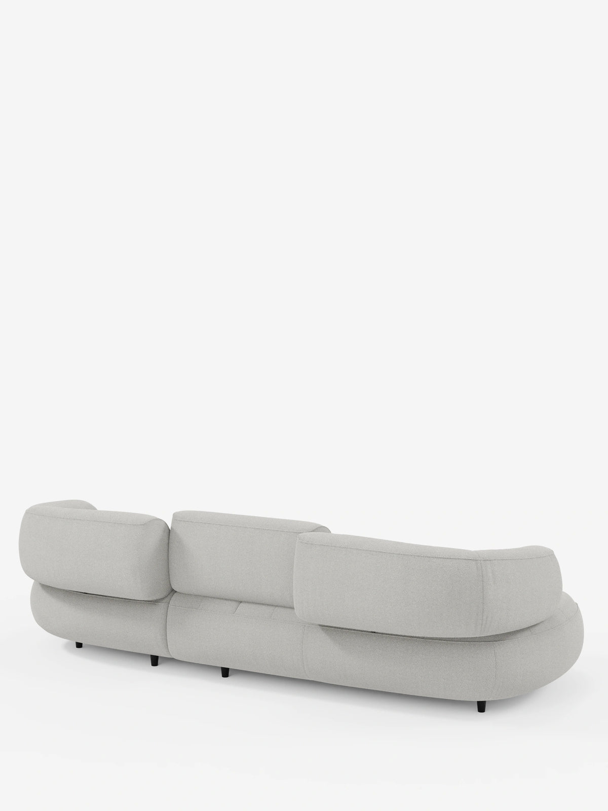 Un divano angolare “Croissant” di colore grigio chiaro, dal design a forma di fagiolo e con schienali scorrevoli, rivestito in morbido tessuto effetto cotone smacchiabile T33; nella foto è visibile da dietro con cuscini arrotondati, tre schienali regolabili e gambe basse nere.