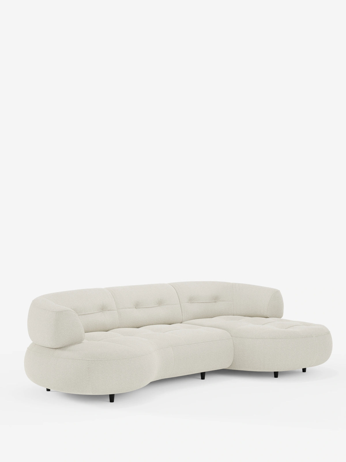 Un divano angolare Croissant color crema, dal design a forma di fagiolo, con schienali scorrevoli in morbido tessuto effetto cotone smacchiabile T33, caratterizzato da una trama trapuntata, forme organiche, bordi arrotondati, schienali bassi e piedini scuri.
