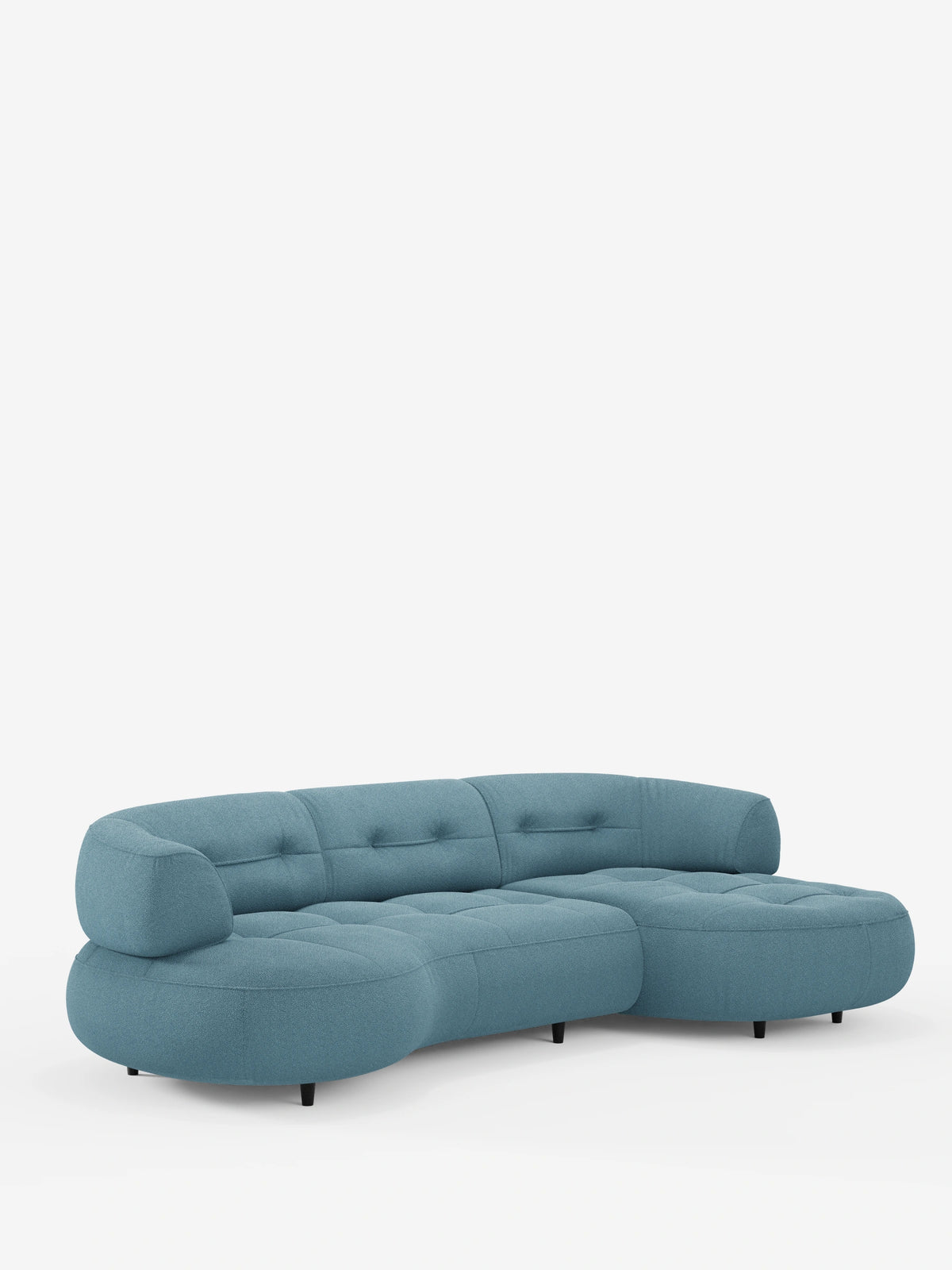 Un divano angolare Croissant a forma di fagiolo, con schienali scorrevoli in morbido tessuto effetto cotone smacchiabile T33 color blu polveroso, con schienali bassi trapuntati e gambe cilindriche scure su sfondo bianco.