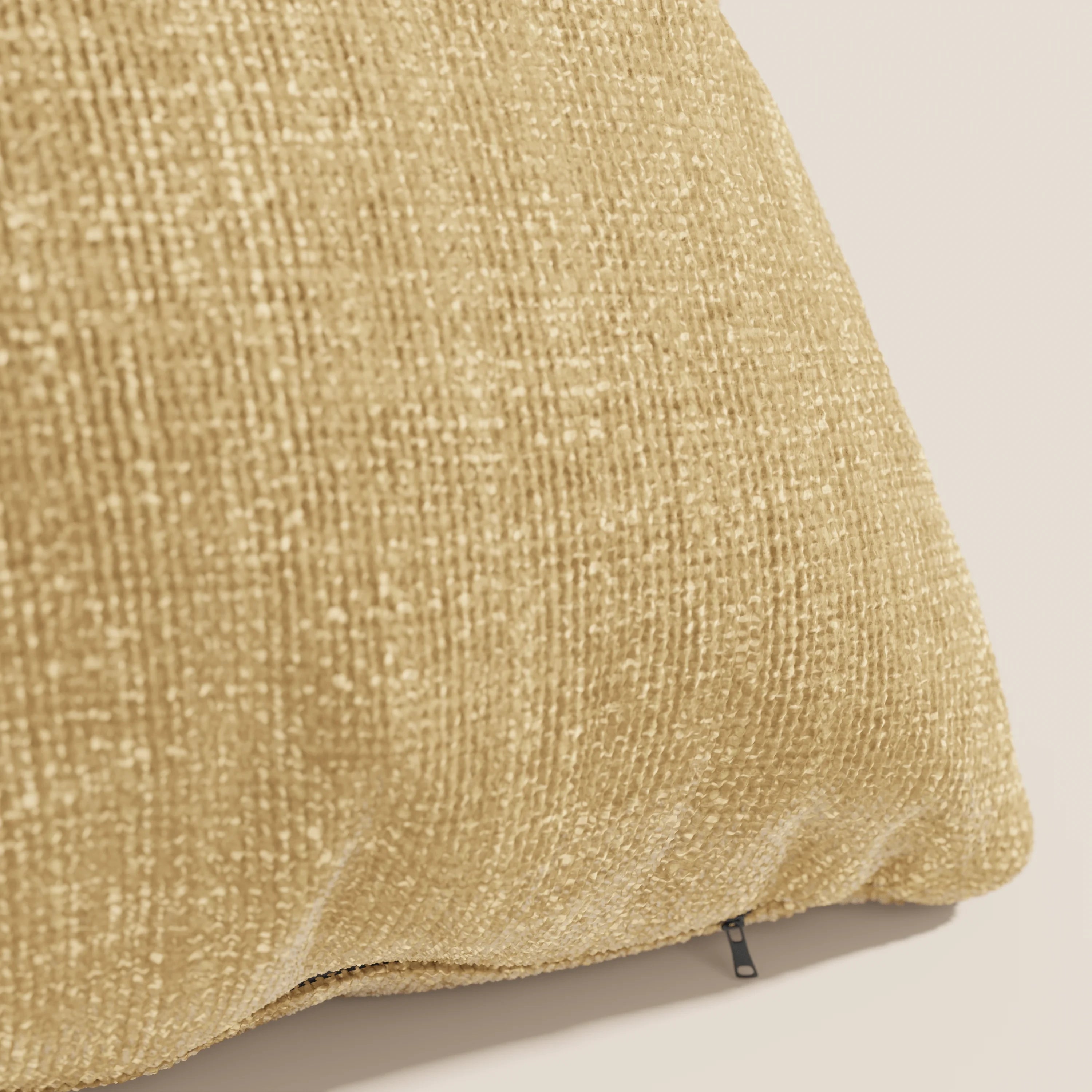 Un primo piano del cuscino Lyon di Divani.Store, in T06 ocra, mostra il suo tessuto morbido e impermeabile e la cerniera inferiore a vista. Il cuscino, di colore marrone chiaro, si staglia su uno sfondo chiaro e semplice, mettendo in risalto il suo design strutturato.