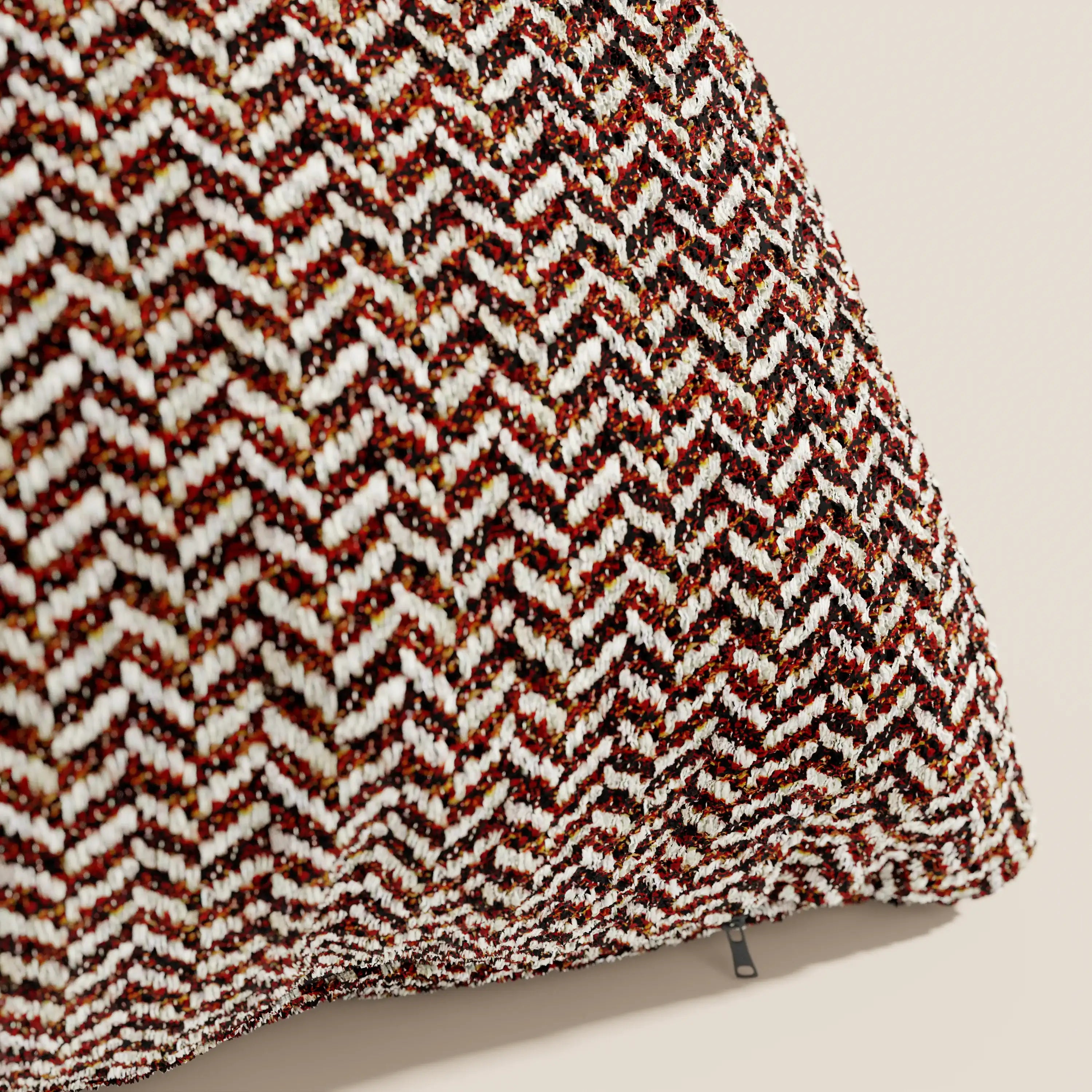 Primo piano del cuscino Sorrento 45x45 in lino di Divani.Store, che mette in risalto il suo morbido tessuto con motivo a chevron nei colori rosso, marrone, nero e bianco: un elegante esempio di cuscini lavabili in lavatrice su uno sfondo beige.