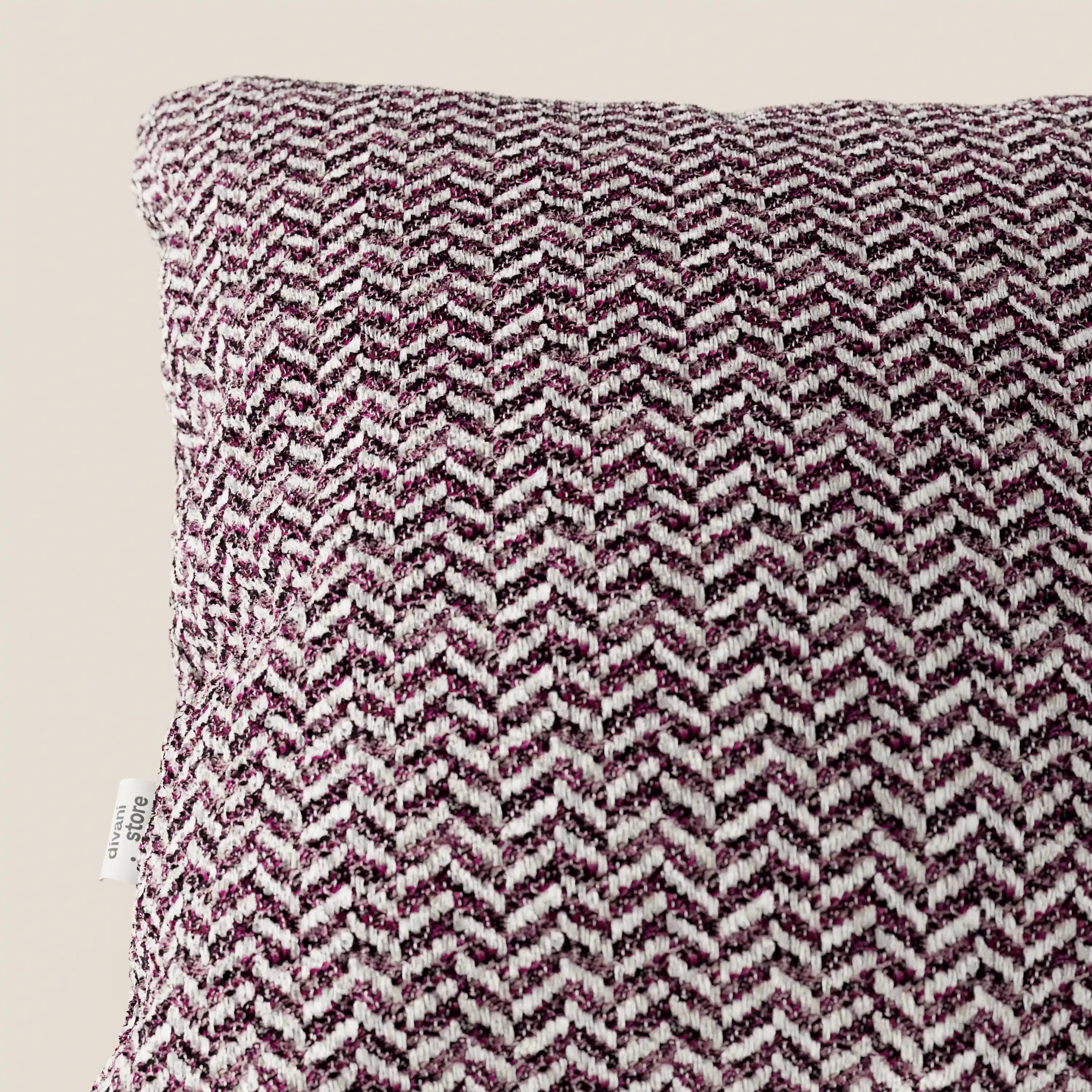 Un primo piano del cuscino Sorrento 45x45 in lino di Divani.Store, caratterizzato da una trama a zigzag in rilievo nei toni del bordeaux e del bianco, lavabile in lavatrice. Una piccola etichetta bianca impreziosisce la cucitura sinistra, su uno sfondo beige neutro.